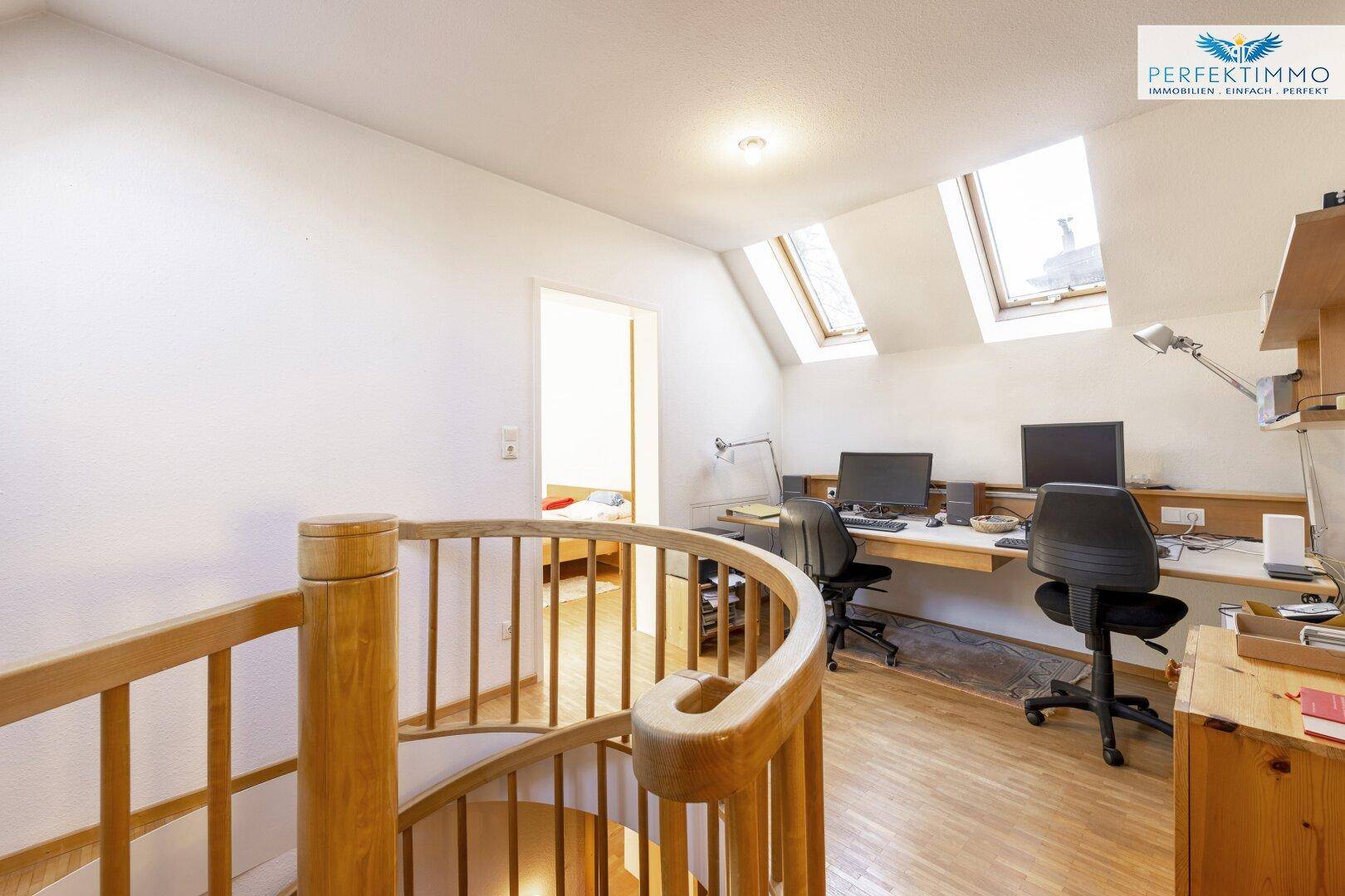 Heller Arbeitsbereich im Dachgeschoss mit Schreibtischen, Holztreppe und Dachfenstern für natürliches Licht.