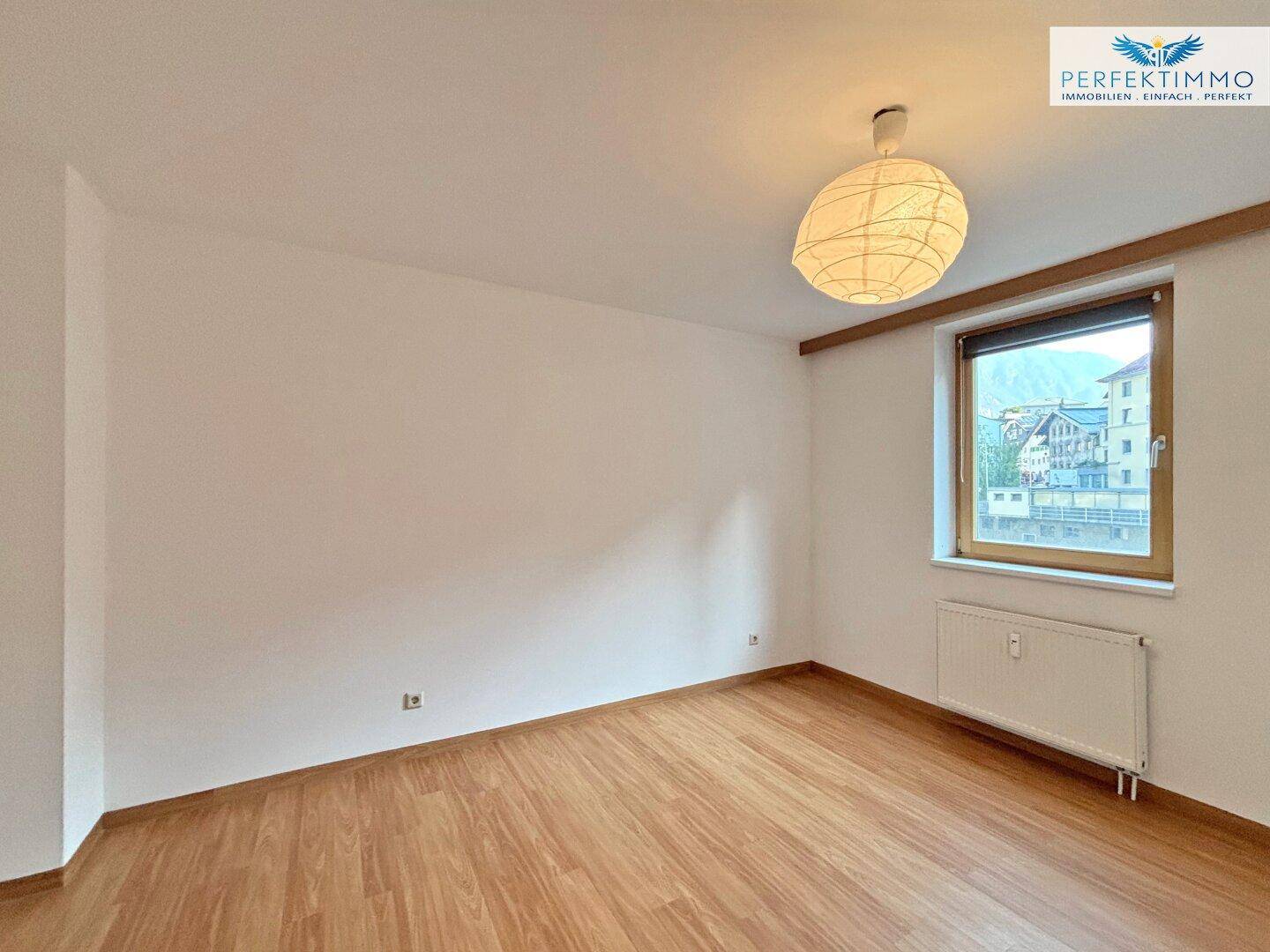 Schlafzimmer mit Parkettboden, weiß gestrichenen Wänden und Fenster mit Bergblick.