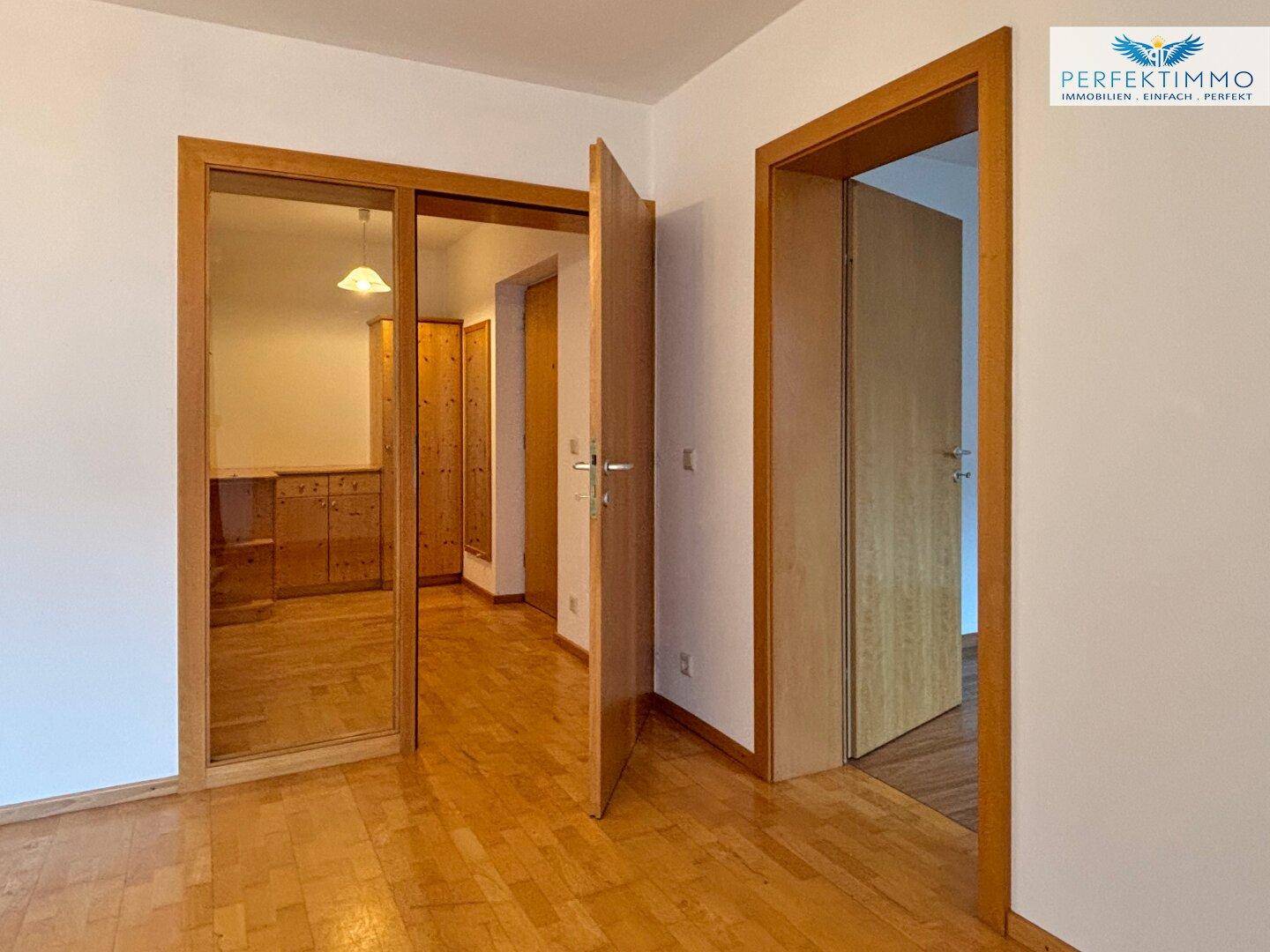 Heller Flur mit Holzparkett und einem großen Spiegelschrank, der den Raum optisch erweitert.