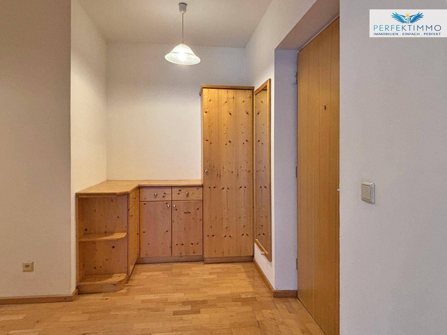 Raum mit hellen Holzmöbeln und Parkettboden, ideal als Ankleidebereich oder Flur.