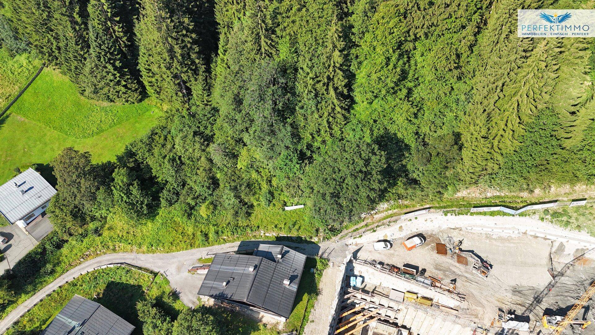 Vogelperspektive eines bewaldeten Grundstücks mit einem Haus und einer aktiven Baustelle.