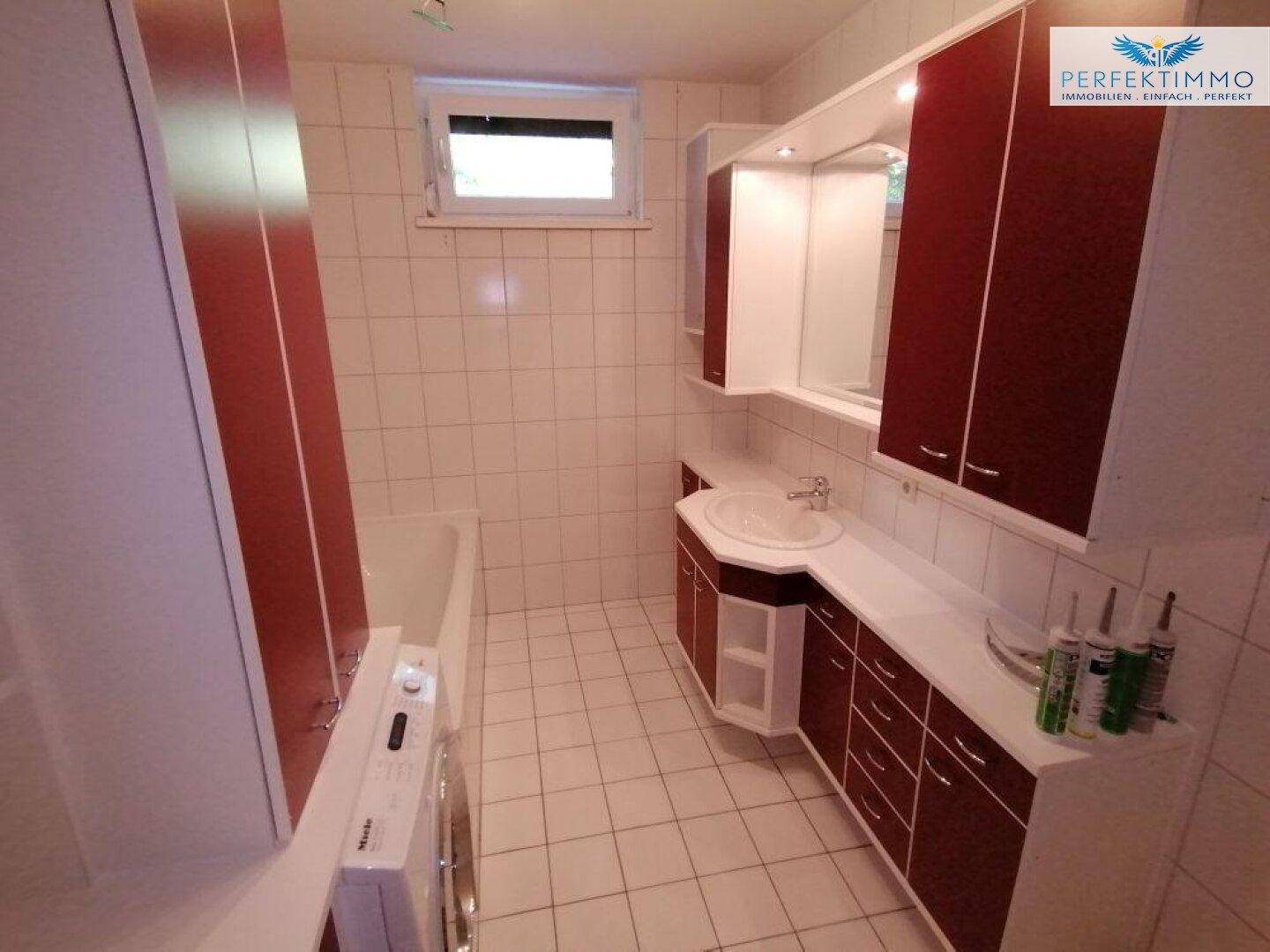 Geräumiges Badezimmer mit Waschbecken, Dusche, Waschmaschine und Fenster.