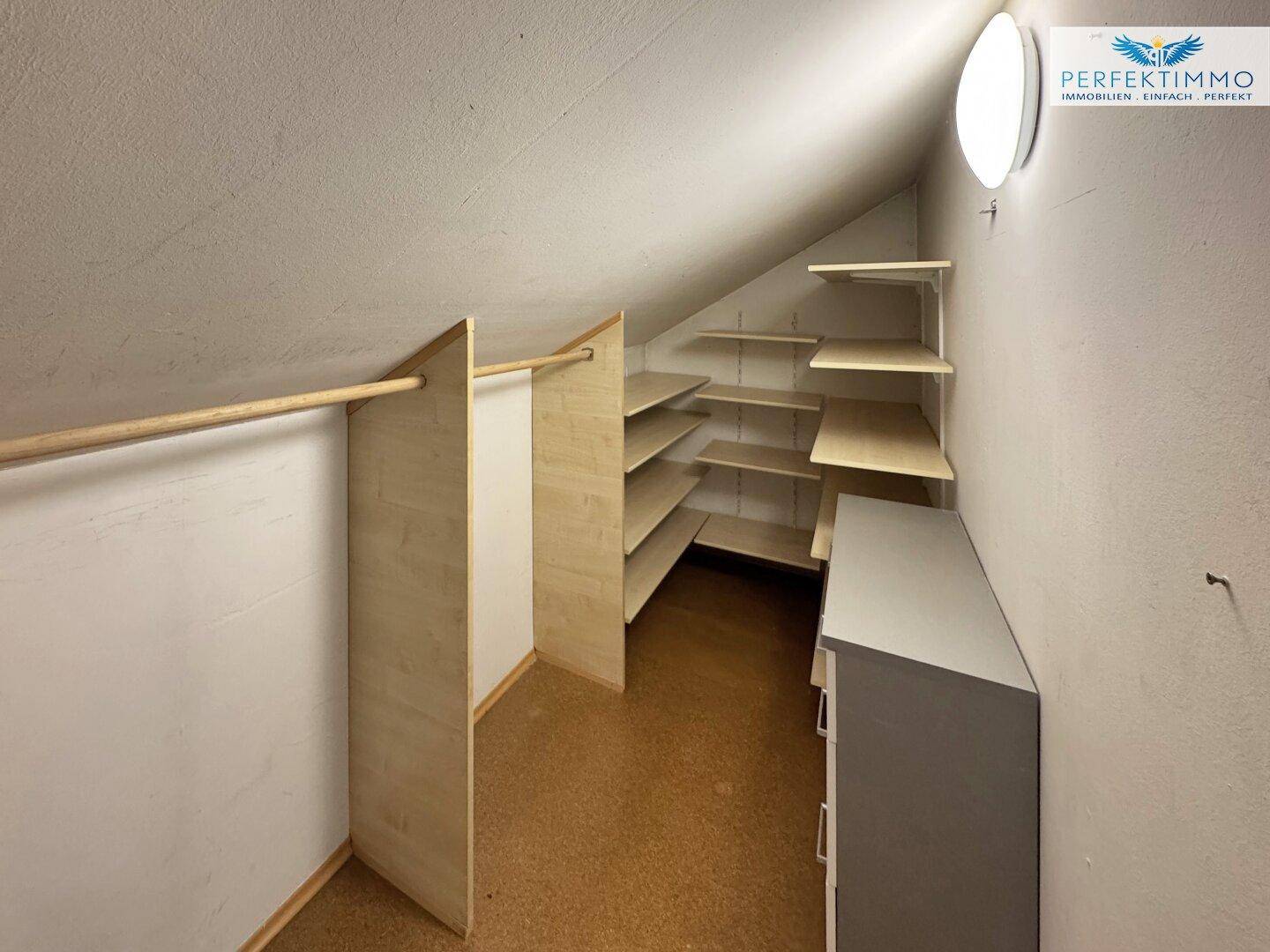 Praktischer Abstellraum mit Regalen und Kleiderstange unter einer Dachschräge, ideal für Stauraum.