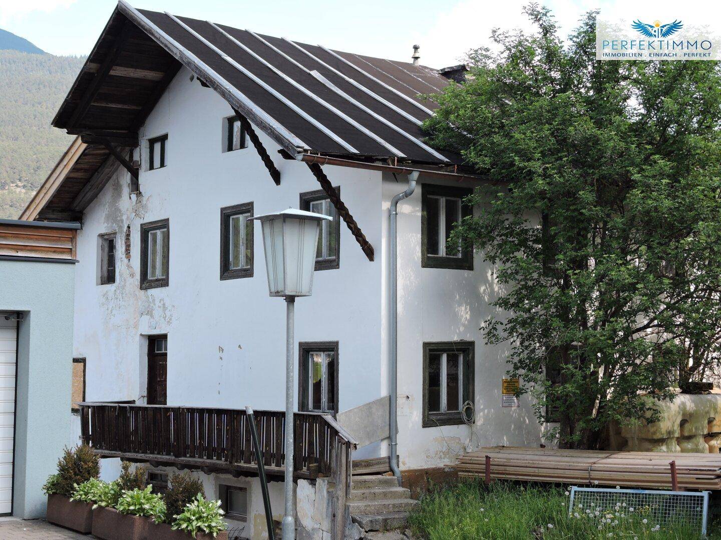Altes Wohnhaus mit weißer Fassade, dunklem Dach und traditionellen Holzelementen.
