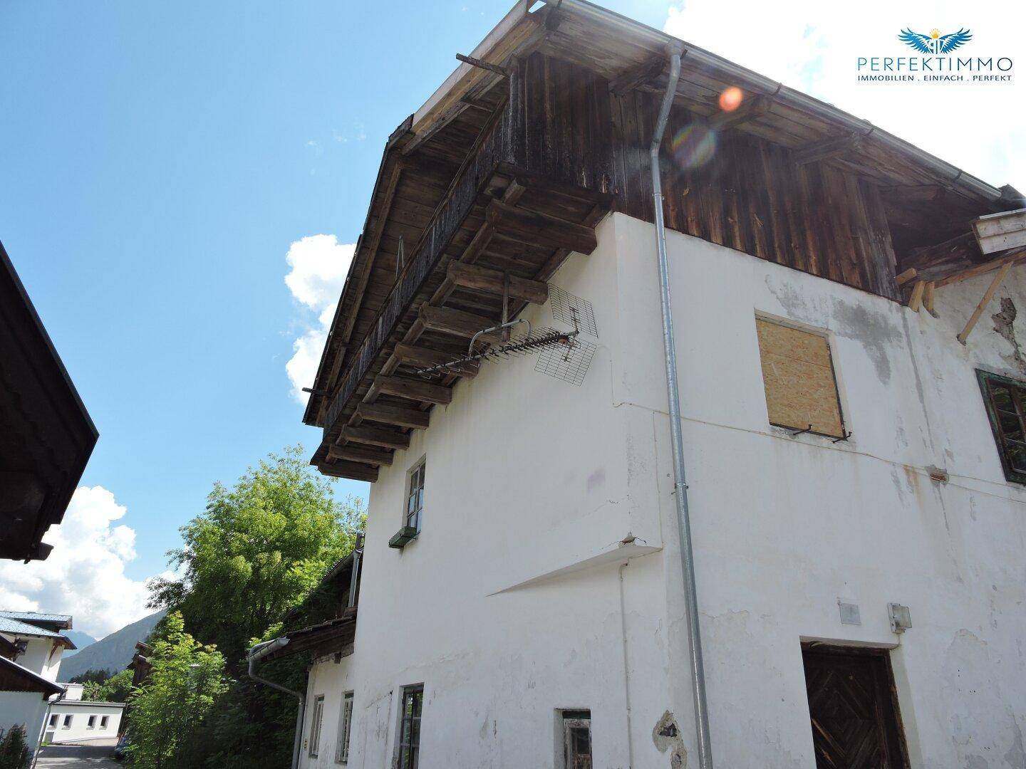 Seitenansicht des alten Hauses mit sichtbarer Holzkonstruktion und traditionellem Dachüberstand.
