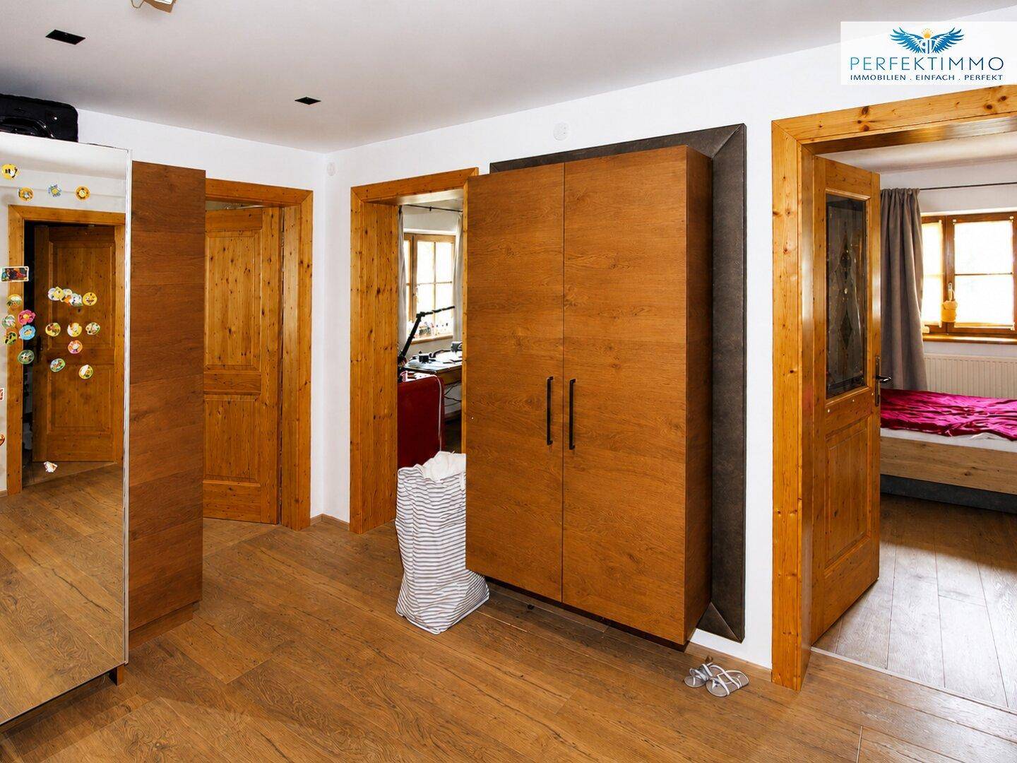 Heller Flur mit Holzfußboden und einem modernen Kleiderschrank zwischen den Zimmern.