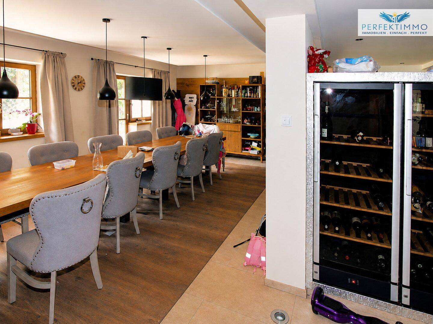 Großer Essbereich mit langem Holztisch, bequemen Stühlen und Weinkühlschrank.