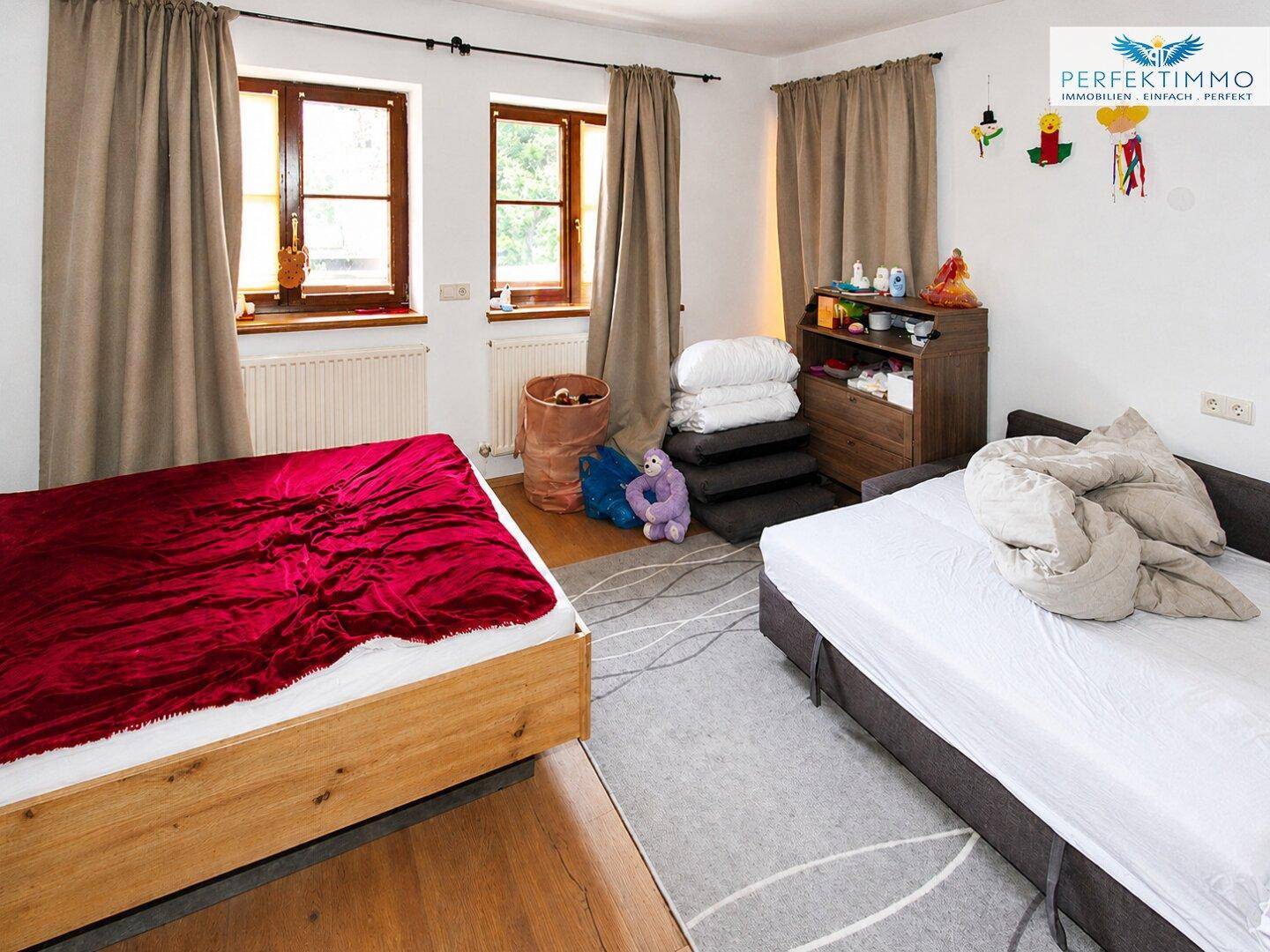 Geräumiges Schlafzimmer mit zwei Betten, Teppichboden und natürlichem Lichteinfall.