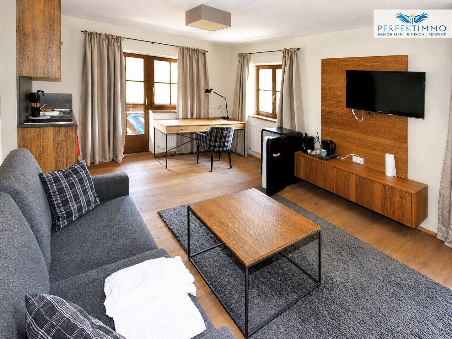 Modern eingerichtetes Wohnzimmer mit Sofa, Schreibtisch und integrierter Medieneinheit.