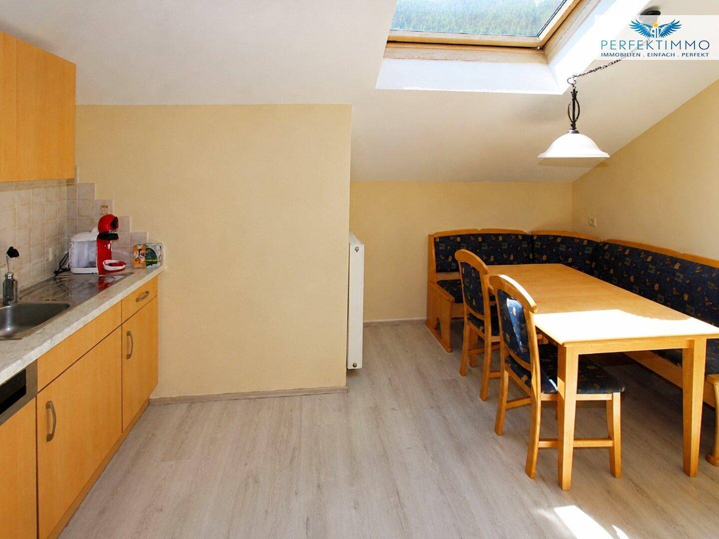 Helle Küche mit Essbereich, Holzschränken und Dachfenster für natürliches Licht.