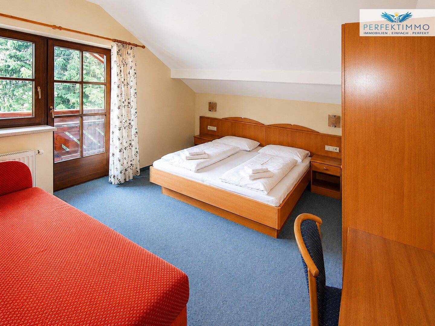 Geräumiges Schlafzimmer im Dachgeschoss mit Doppelbett und Zugang zum Balkon.