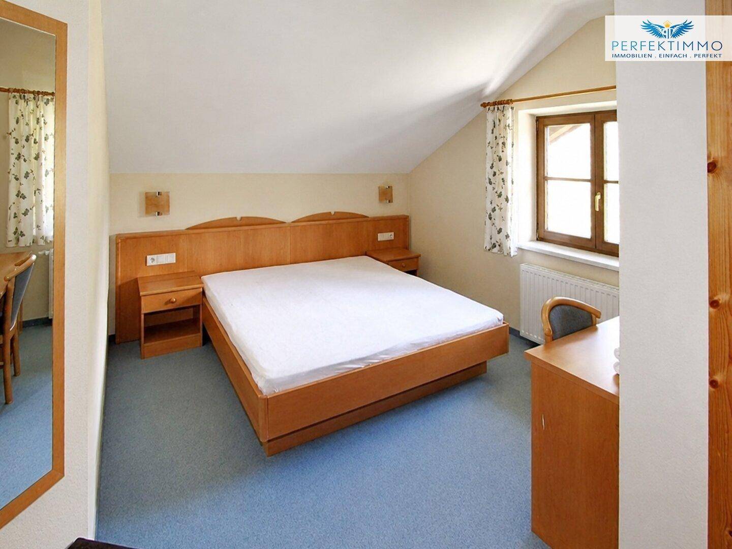 Gemütliches Schlafzimmer im Dachgeschoss mit Doppelbett, Holzboden und Fenster.