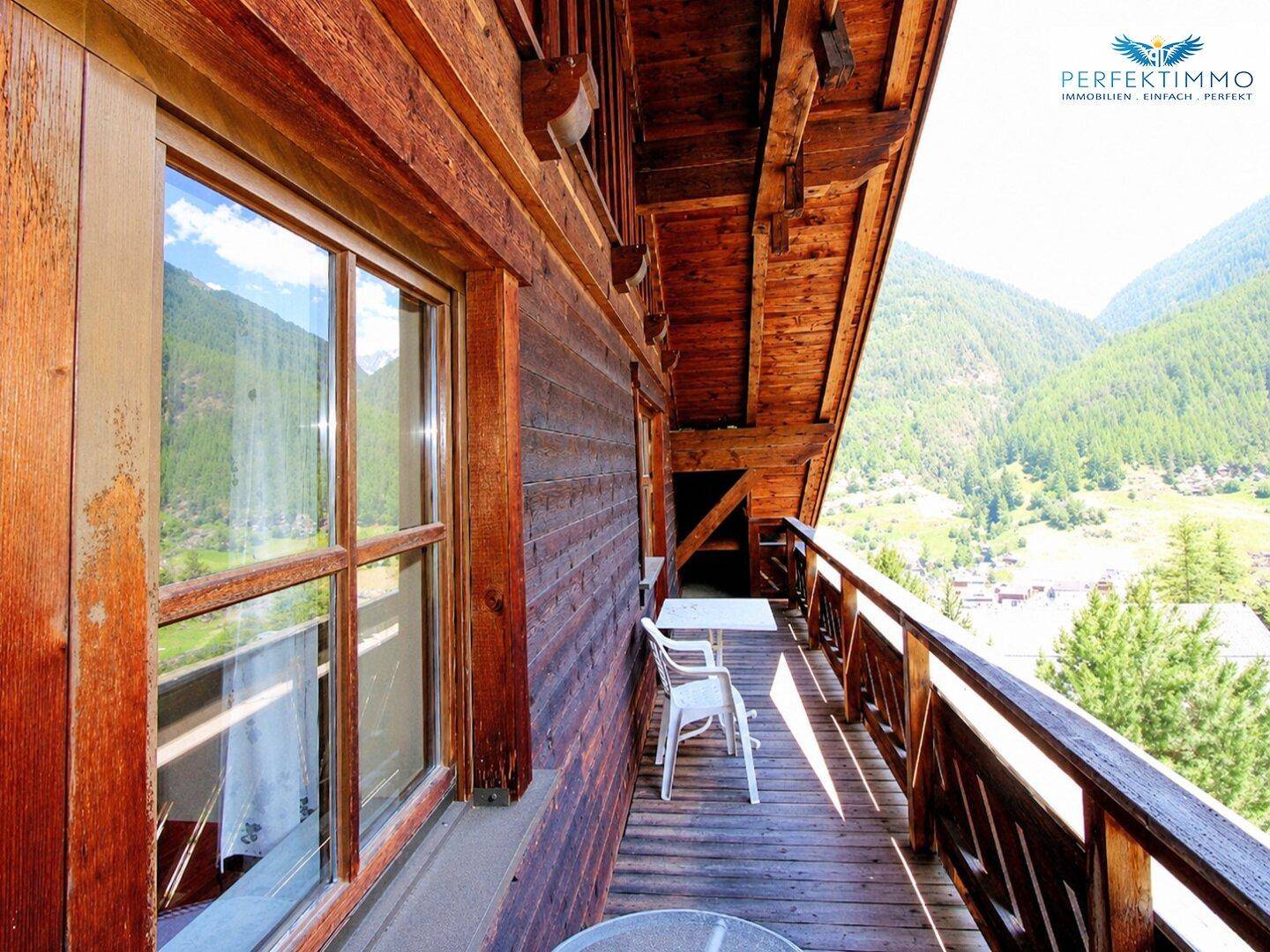 Langer Holzbalkon mit Bergblick und Sitzgelegenheiten, ideal zum Entspannen.