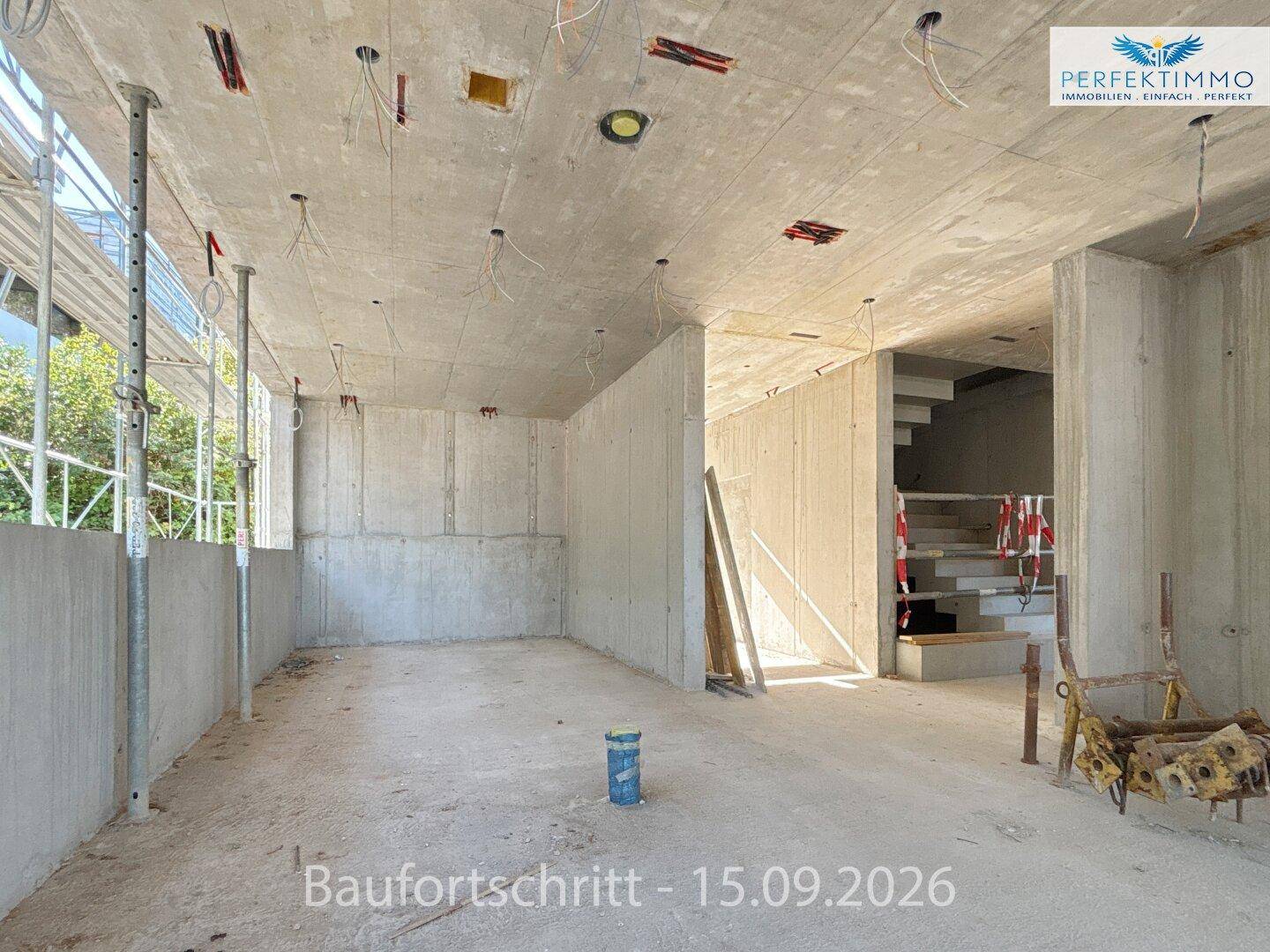Rohbau-Innenraum mit Betonwänden, Decken und einem sichtbaren Treppenaufgang im Hintergrund.