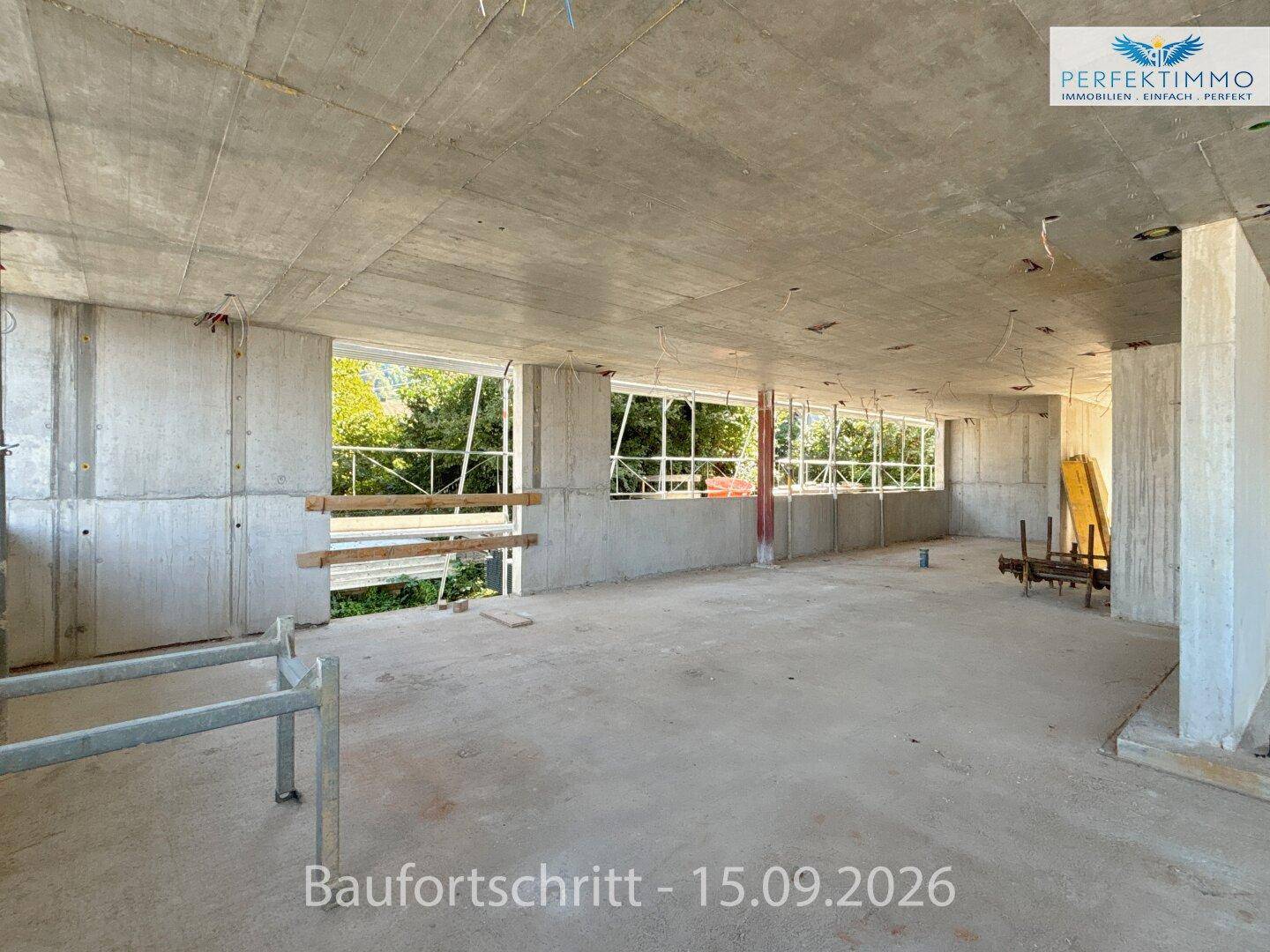 Langer Rohbau-Innenraum mit durchgehenden Fensteröffnungen, die viel natürliches Licht hereinlassen.