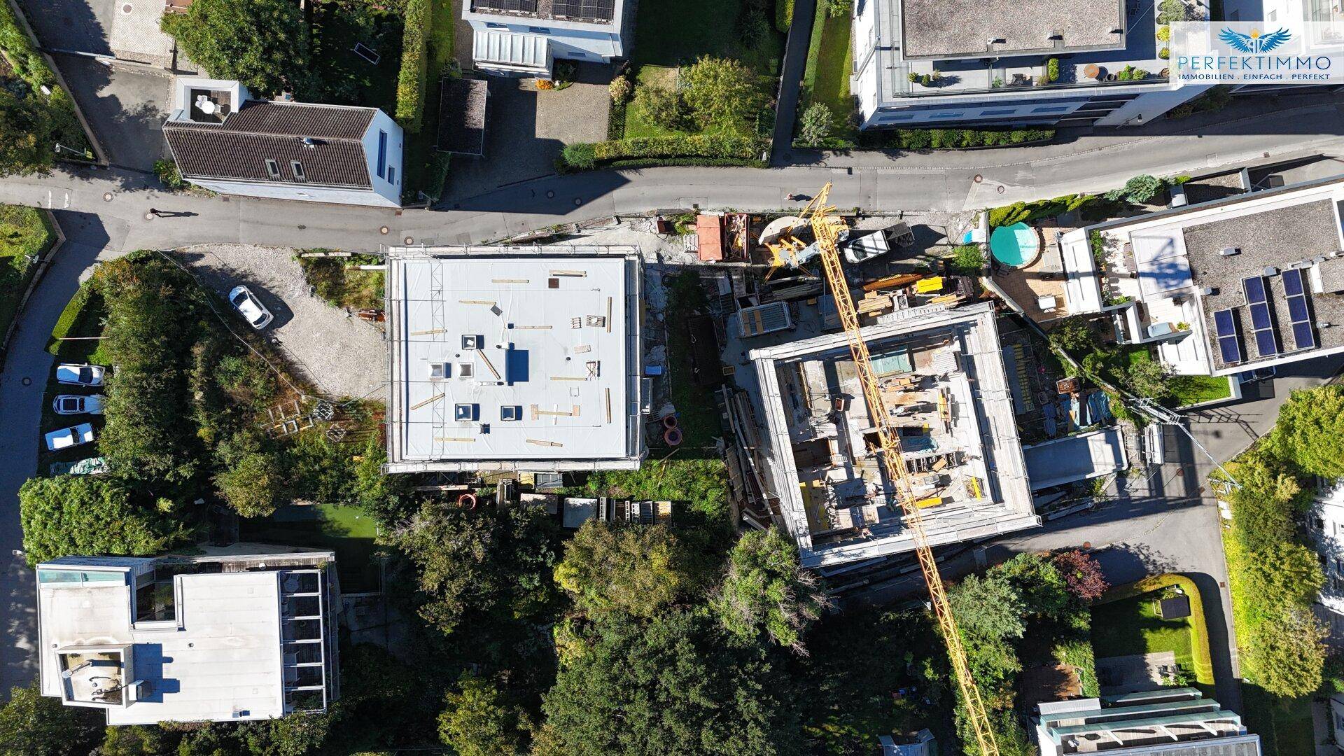 Senkrechte Luftaufnahme der Baustelle mit zwei Gebäuden und der umliegenden Wohnbebauung.