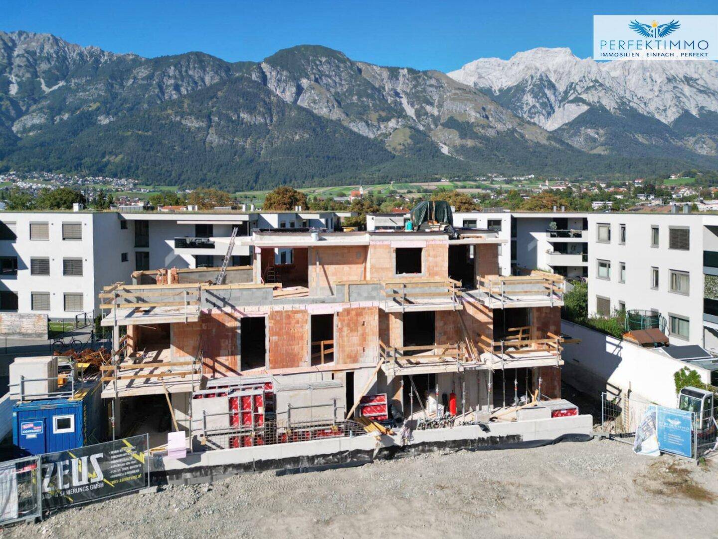Neubau im Rohbauzustand mit Gerüst und Blick auf die umliegende Berglandschaft.