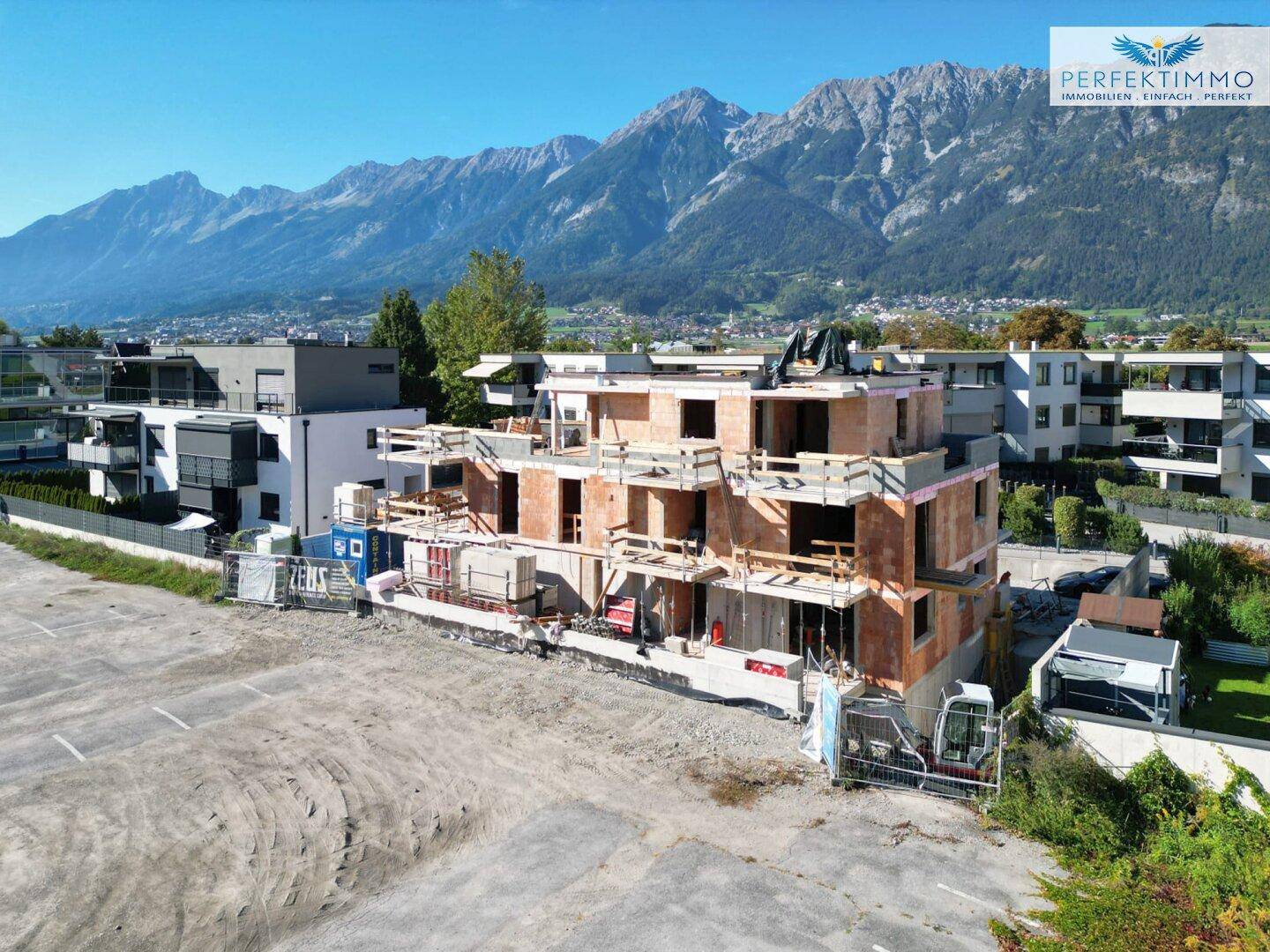 Baustelle eines neuen Wohngebäudes mit klarer Sicht auf die majestätischen Berge im Hintergrund.