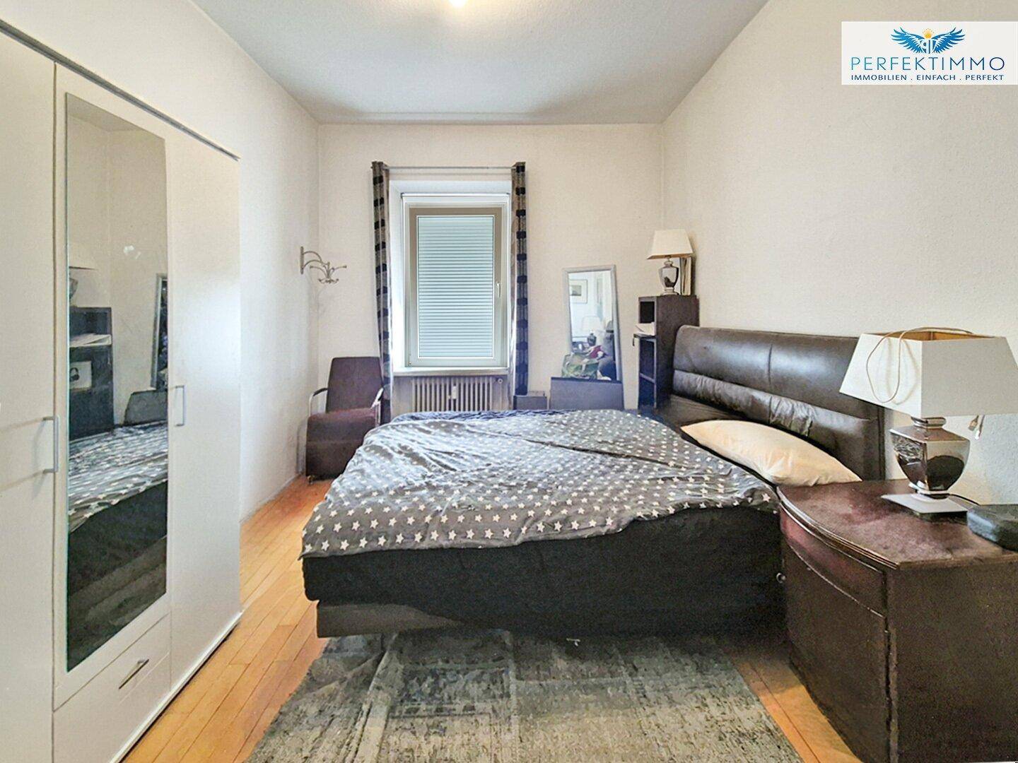 Schlafzimmer mit Doppelbett, großem Kleiderschrank und Parkettboden.