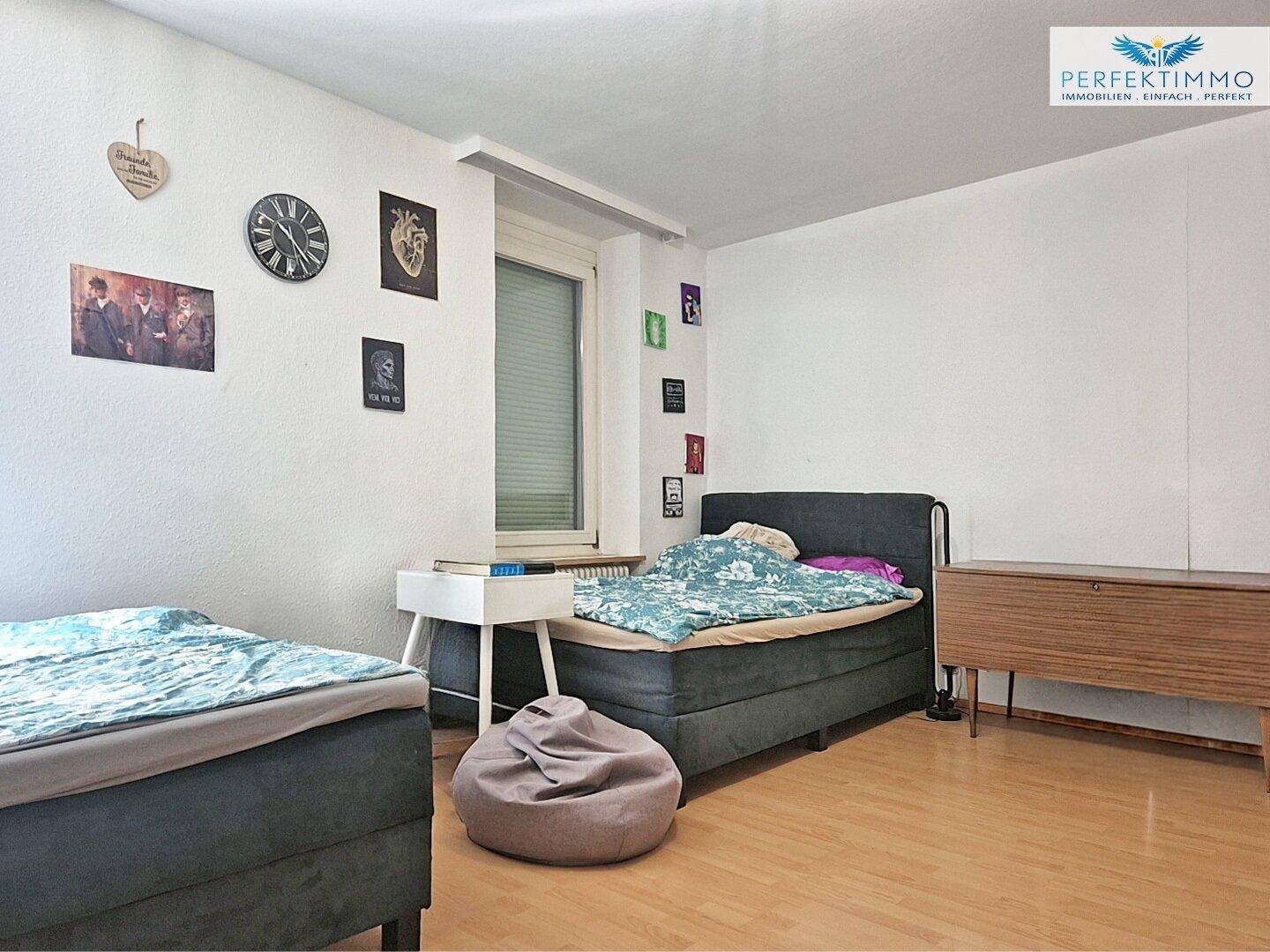Jugendzimmer mit zwei Einzelbetten, Parkettboden und moderner Wanddekoration.