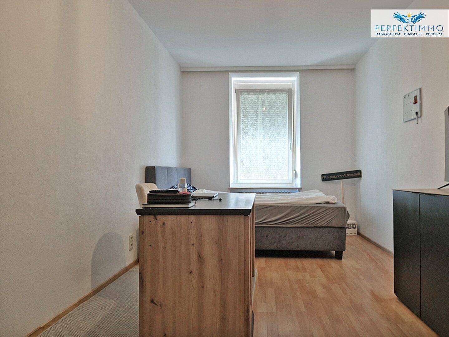 Schlafzimmer mit Einzelbett, Schreibtisch und Parkettboden, ideal als Arbeits- oder Gästezimmer.