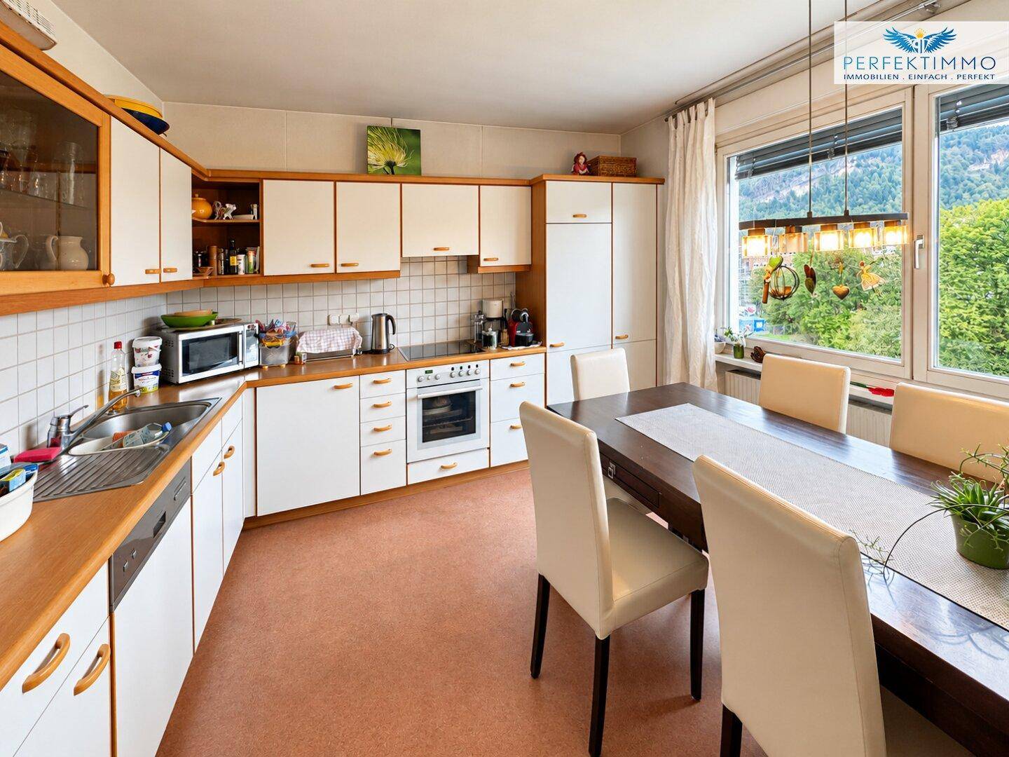 Geräumige Wohnküche mit Einbauküche, Essbereich und Fenster mit Blick ins Grüne.