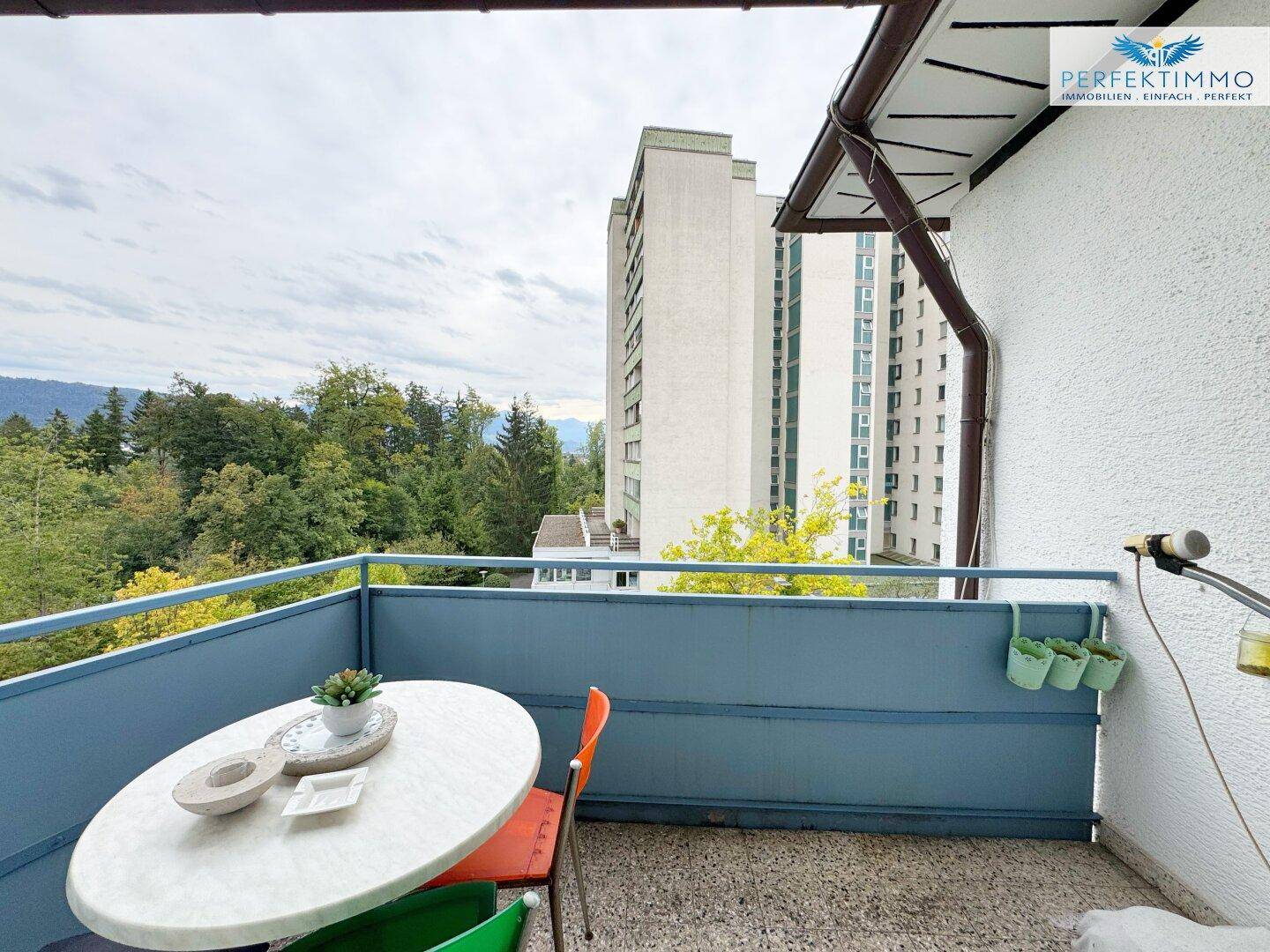 Balkon mit Tisch und Stühlen bietet einen weiten Blick auf die umliegende Landschaft und Berge.