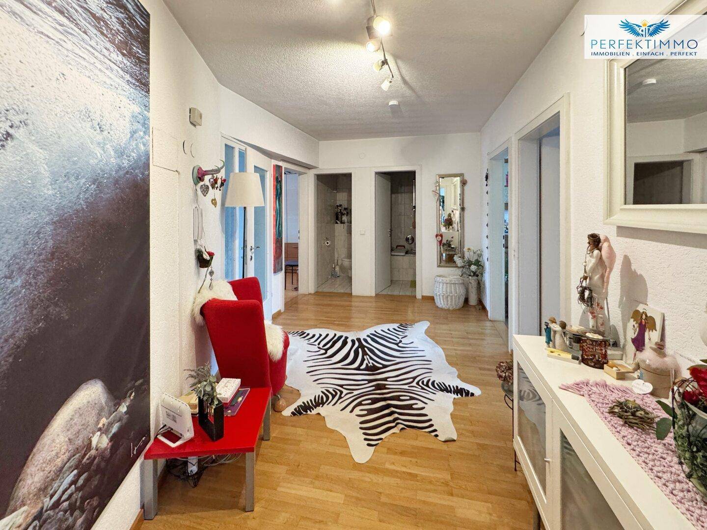 Heller Flur mit Parkettboden, dekorativem Zebra-Teppich und Zugang zu mehreren Zimmern.