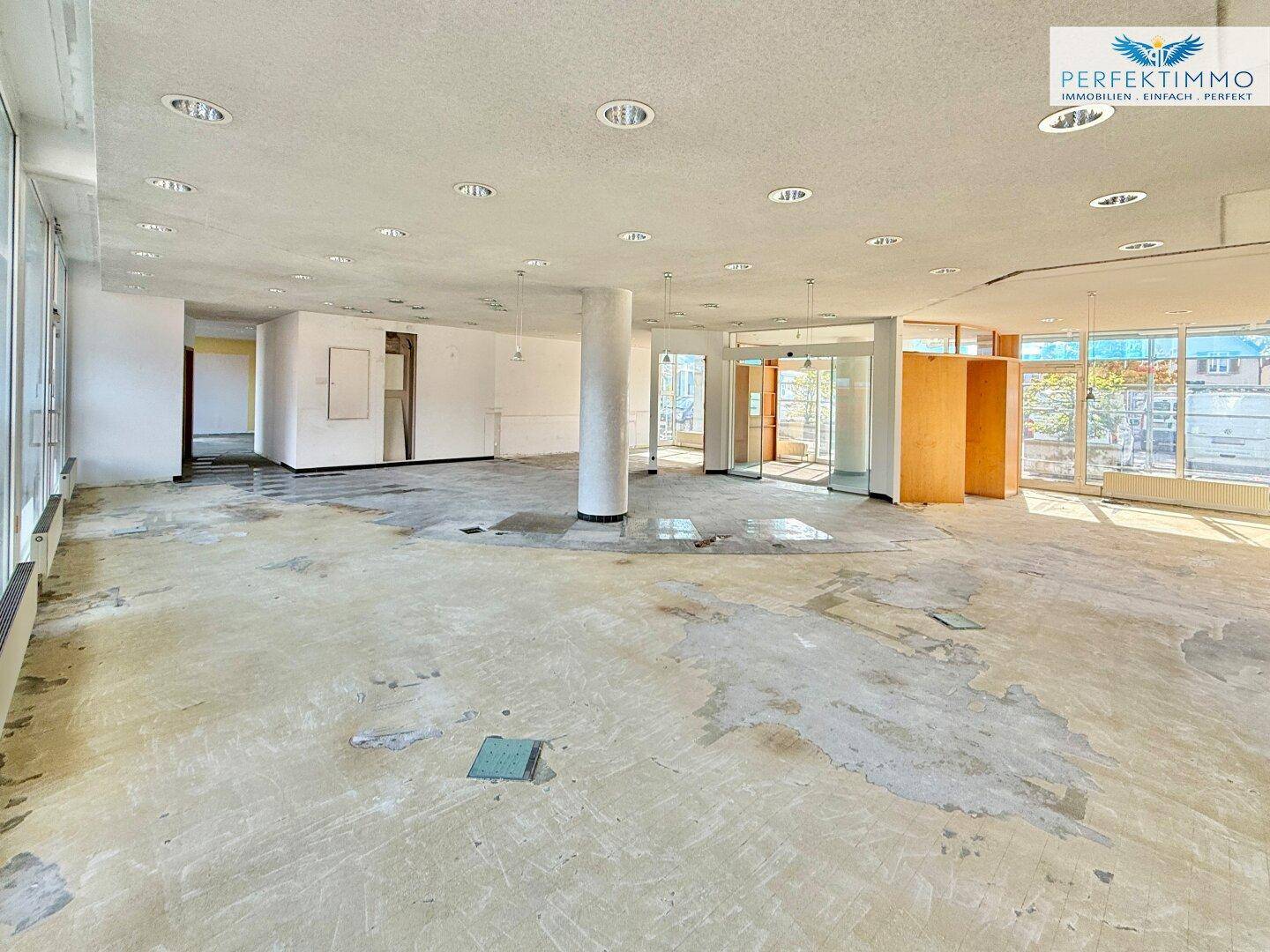 Weitläufiger Gewerberaum mit Säulen und großen Fensterfronten, ideal für flexible Nutzung und viel Licht.