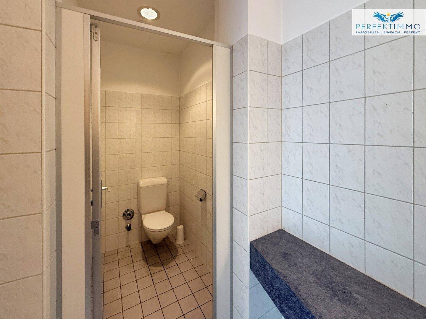 Saubere Toilettenkabine mit gefliesten Wänden und Boden, ausgestattet mit einer modernen Toilette.