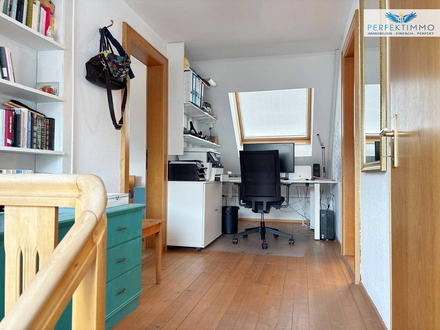 Helles Arbeitszimmer im Dachgeschoss mit Schreibtisch, Bürostuhl und Dachfenster.