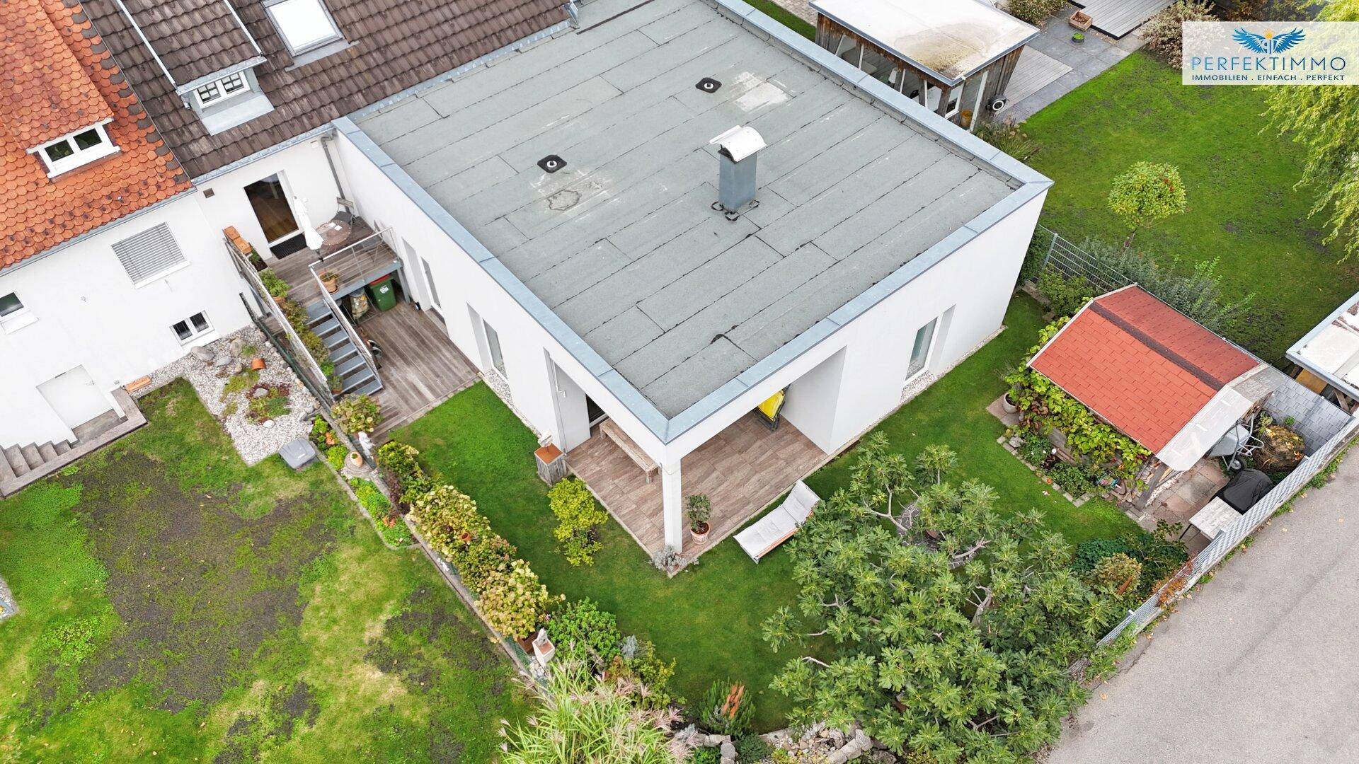 Vogelperspektive des Hauses mit Flachdach, überdachter Terrasse und gepflegtem Gartenbereich.