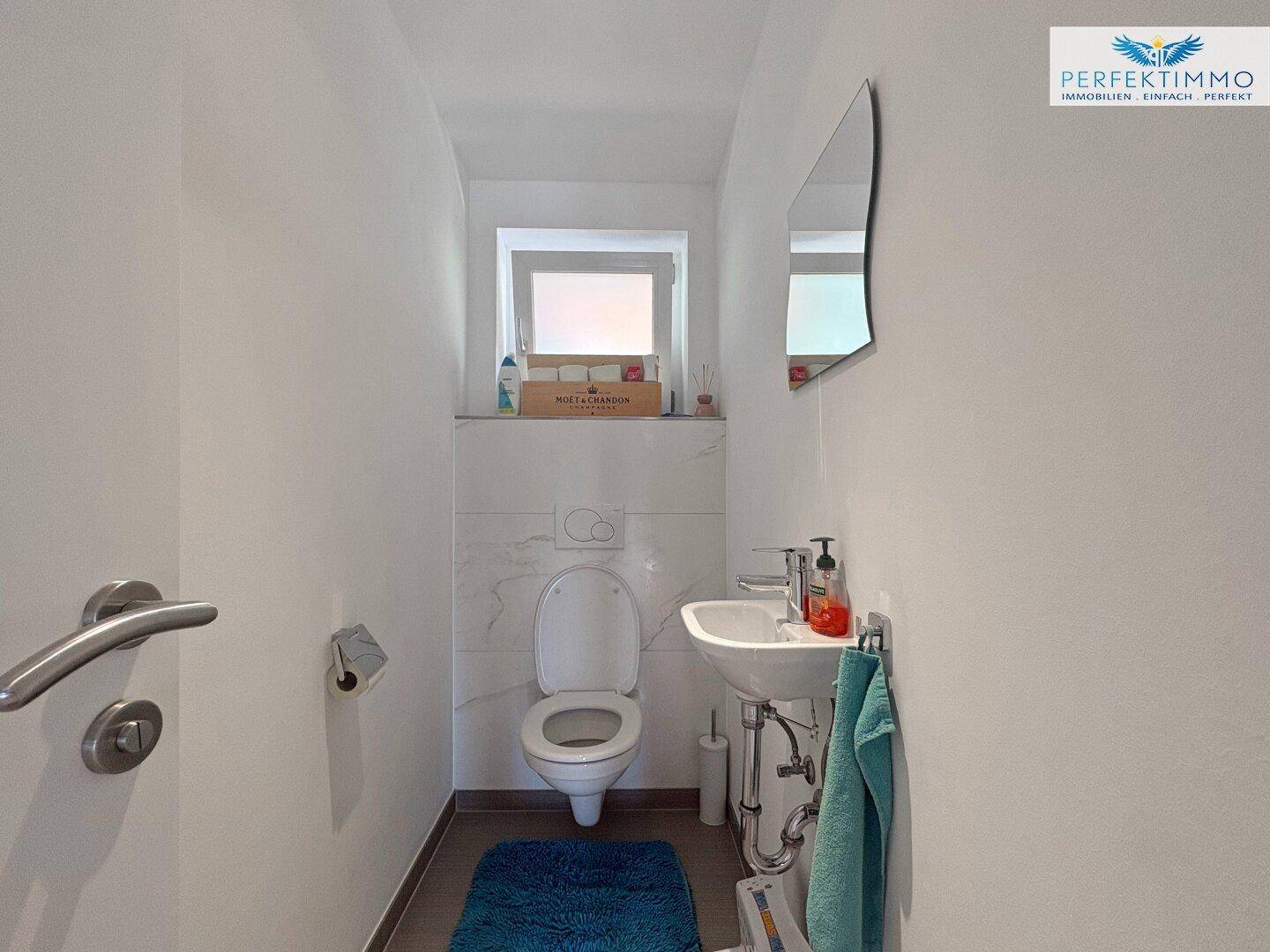 Kleines Gäste-WC mit Fenster, Wand-WC und Handwaschbecken.