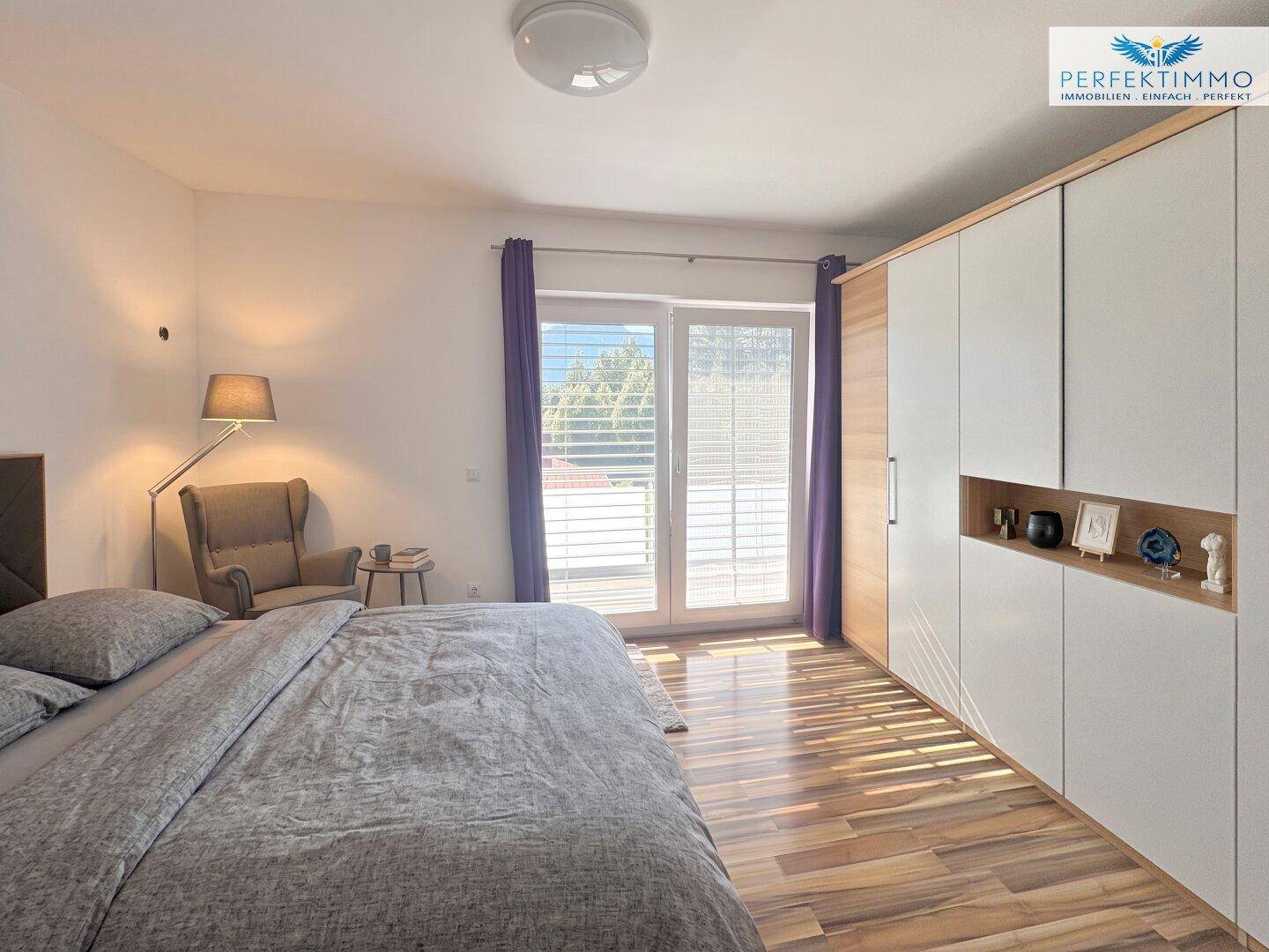 Schlafzimmer mit Holzboden, Einbauschrank und Zugang zu einem Balkon.