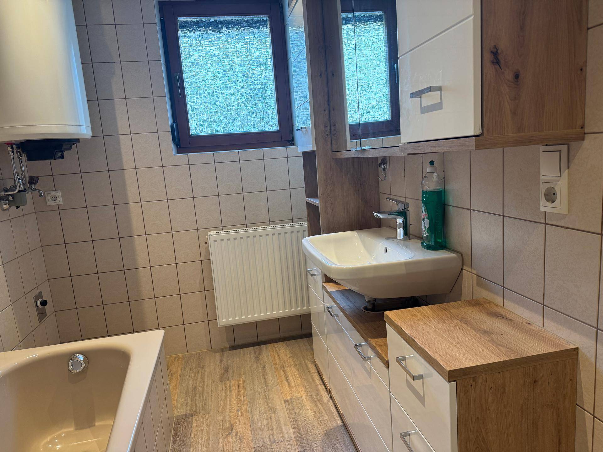 Badezimmer mit Badewanne, Waschbecken und Spiegelschrank.