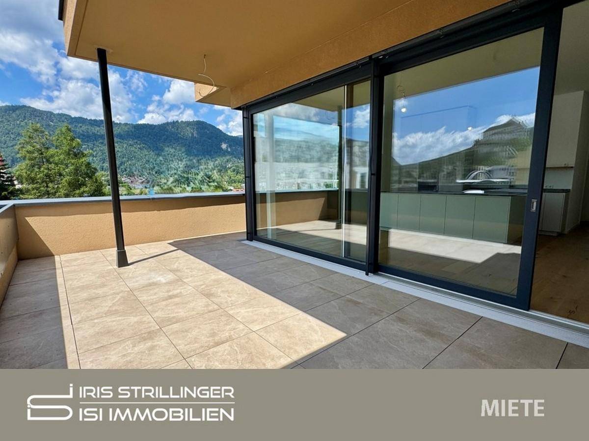 Große, geflieste Terrasse mit weitem Bergblick und Zugang zu einem hellen Innenraum.