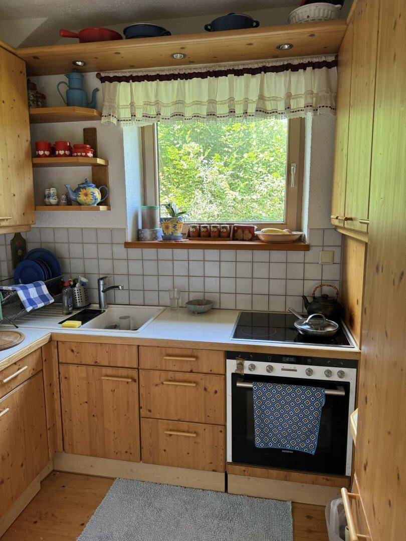 Funktionale Küche im Landhausstil mit Holzschränken, weißen Fliesen und Fenster.