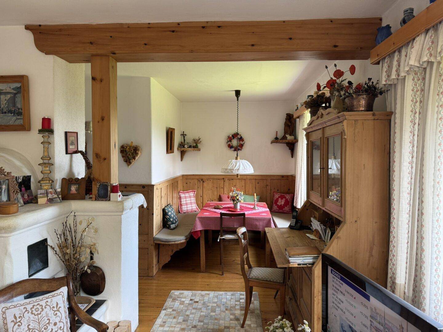 Gemütlicher Essbereich im alpinen Stil mit Holzbalken, Eckbank und traditionellem Kachelofen.
