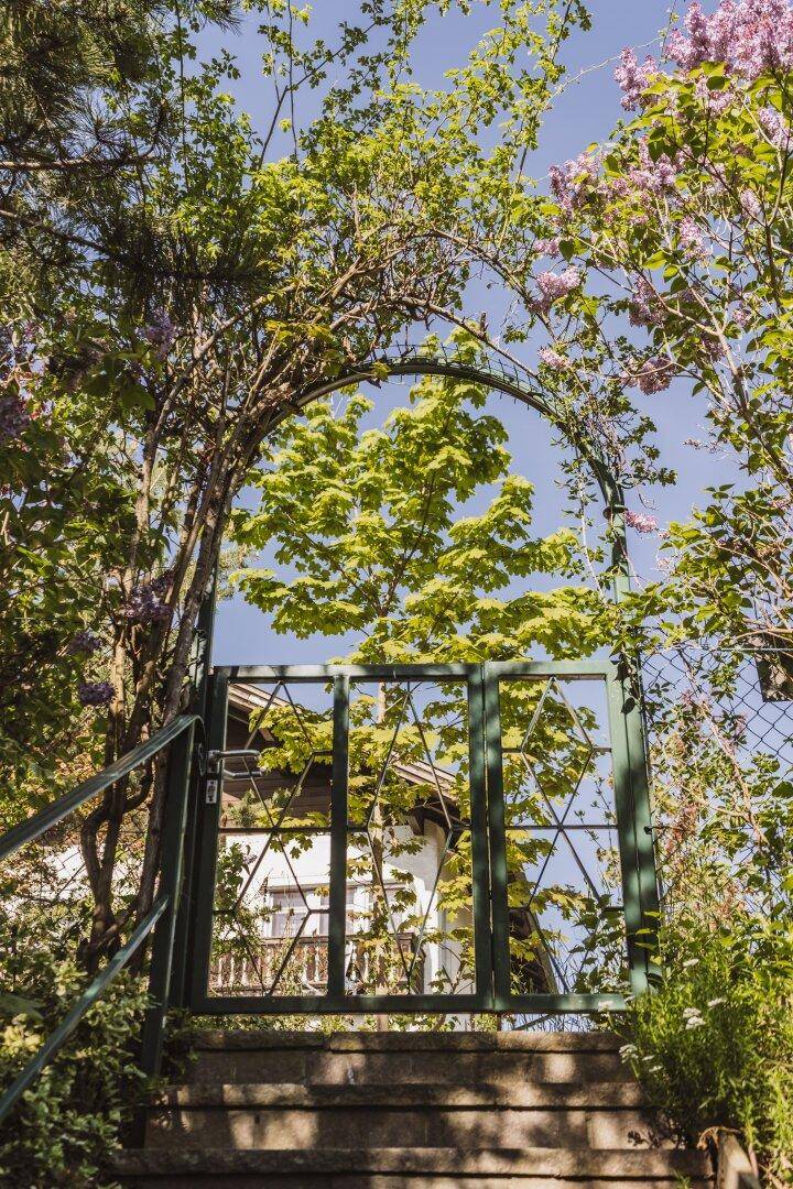 Steintreppe führt durch ein grünes Gartentor zum oberen Bereich des Grundstücks.