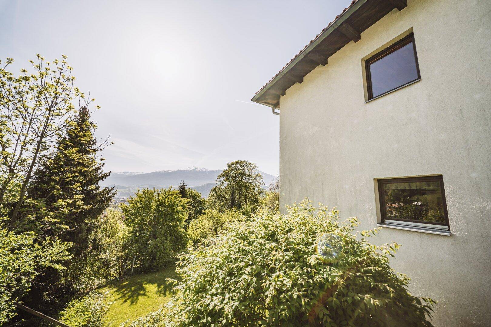 Seitenansicht des Hauses mit weitem Blick über grüne Hügel und Berge.