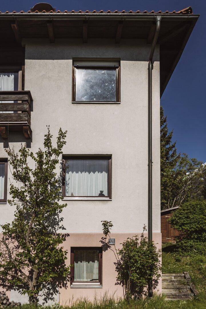 Detailansicht der Hausfassade mit Fenstern und einem kleinen Gartenbereich.