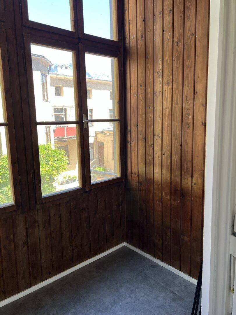 Verglaste Loggia mit Holzvertäfelung und Fenstern, die viel Licht hereinlassen.