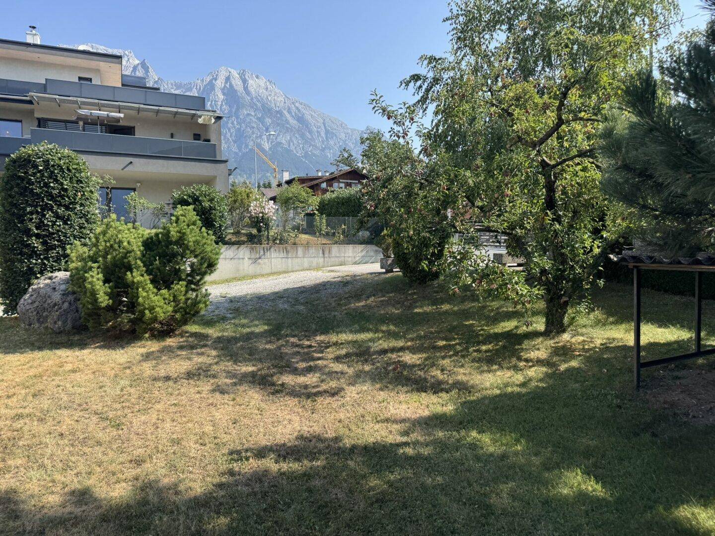 Garten mit Bäumen und Sträuchern, bietet einen weiten Bergblick im Hintergrund.