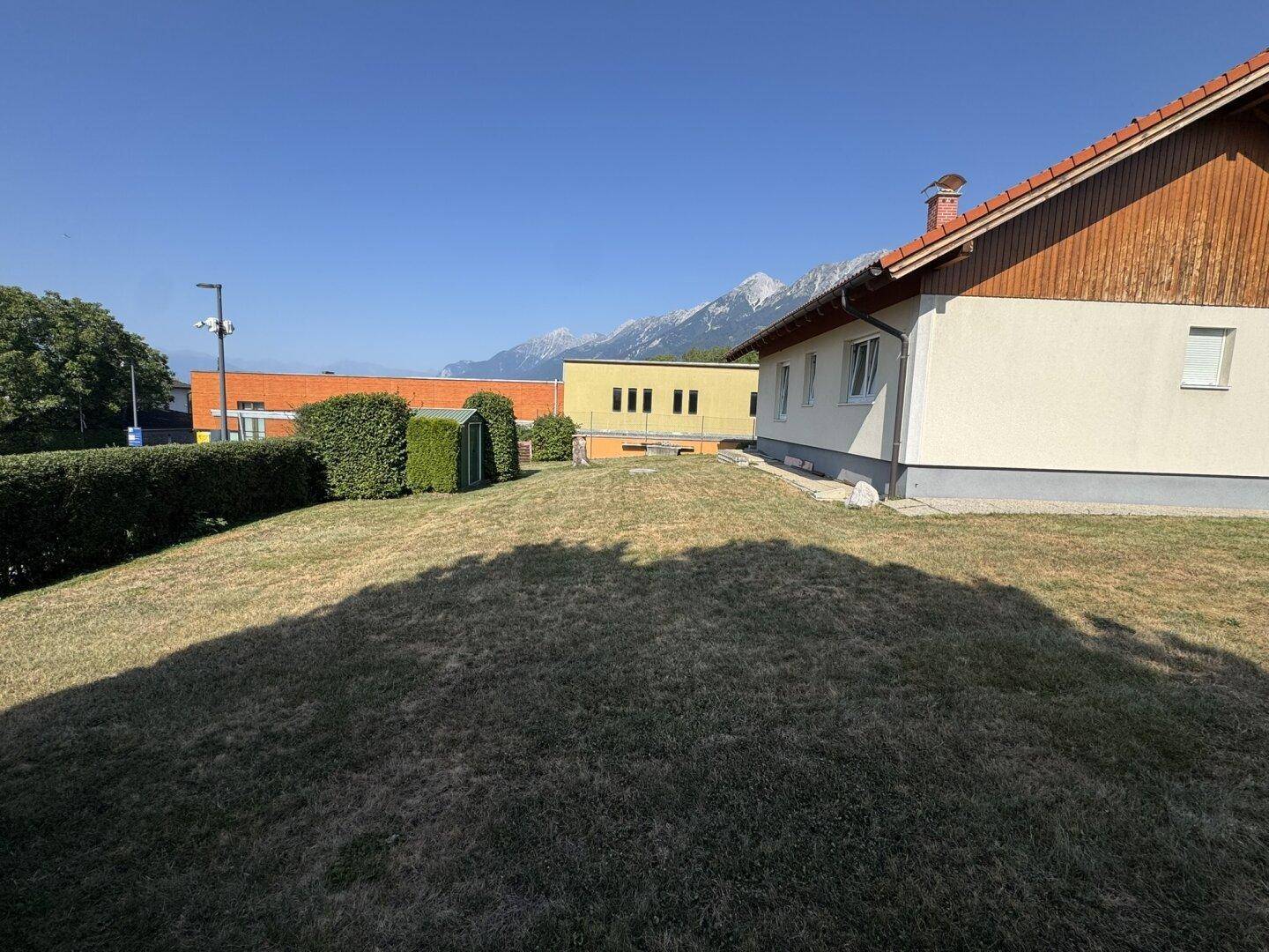 Weitläufiger Garten mit Rasenfläche und Blick auf die umliegenden Gebäude.