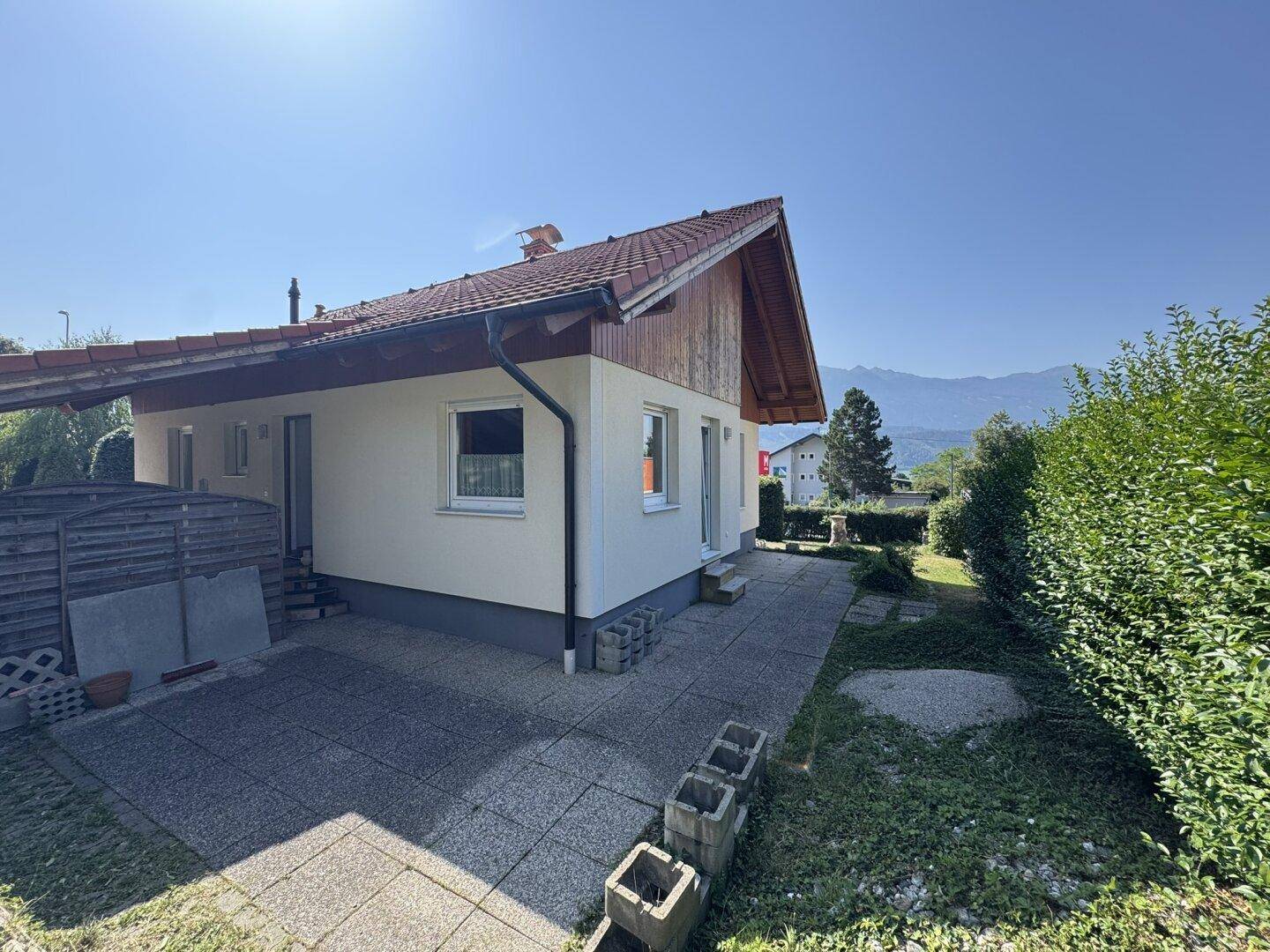 Gepflasterte Terrasse an der Hausseite mit Blick ins Grüne und Hecken.
