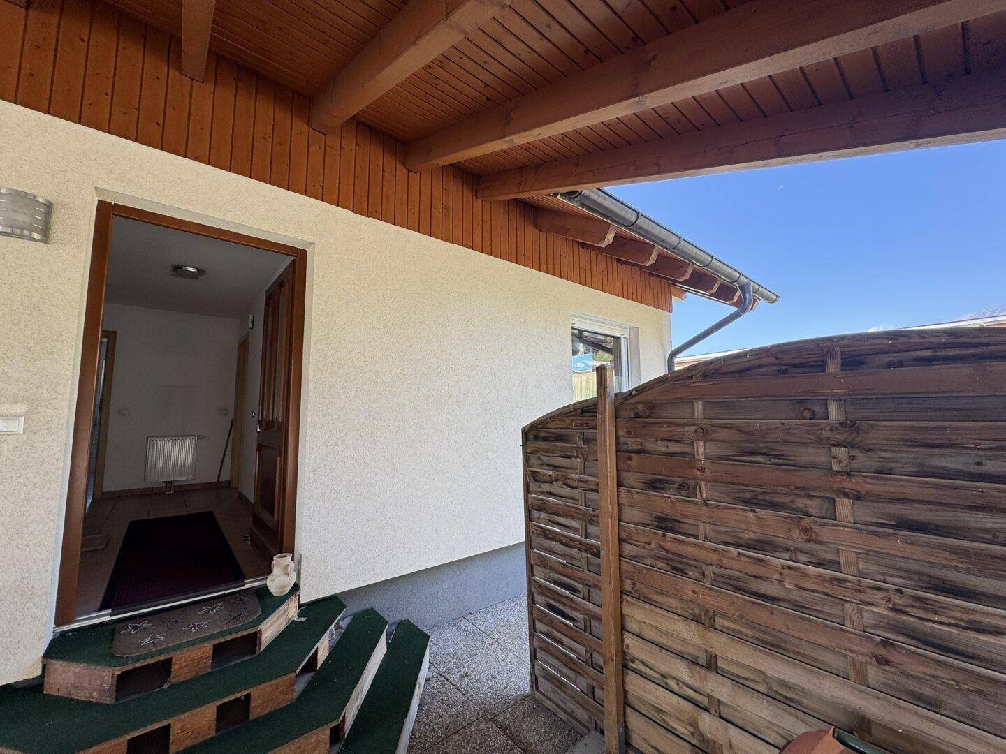 Eingangsbereich des Hauses mit überdachtem Vorbau und Holzbalkendecke.