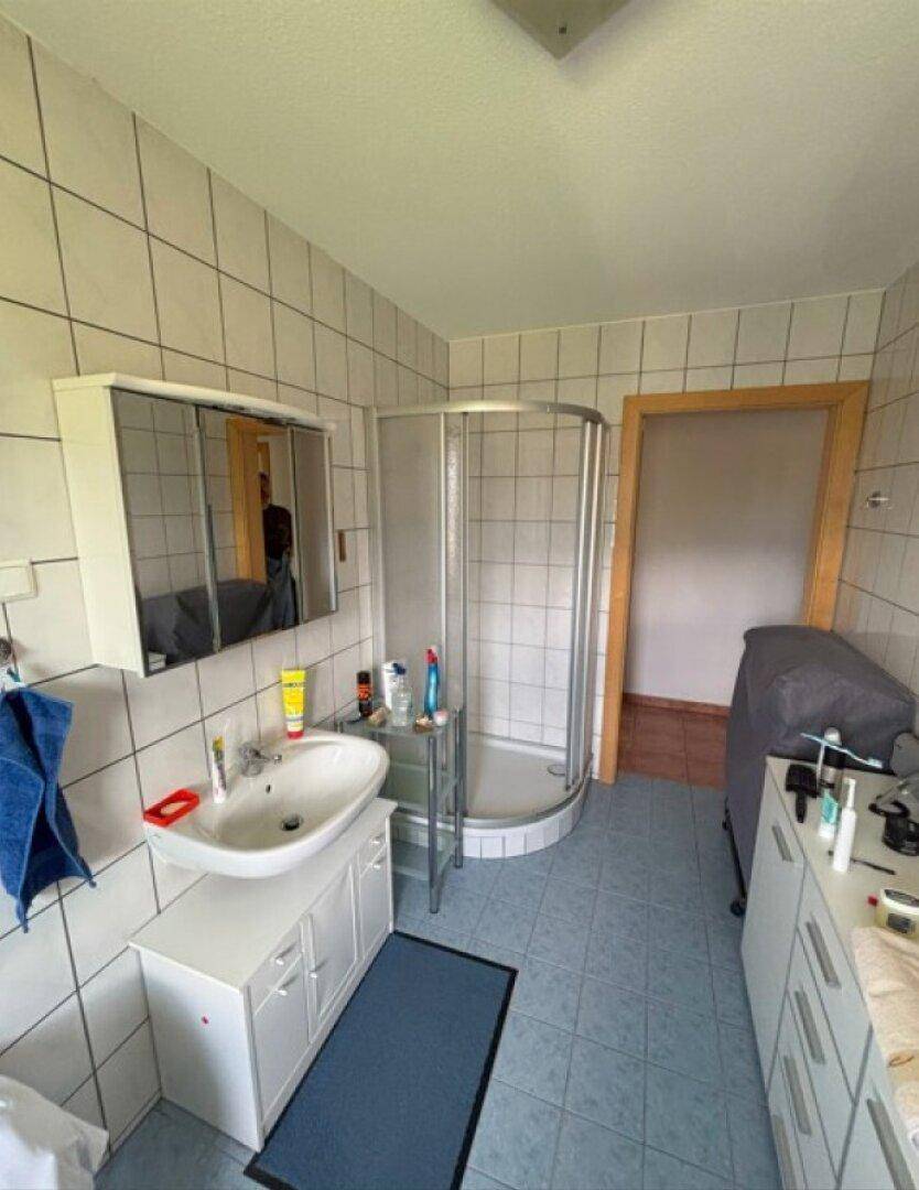 Helles Badezimmer mit Duschkabine, Waschbecken und Spiegelschrank.