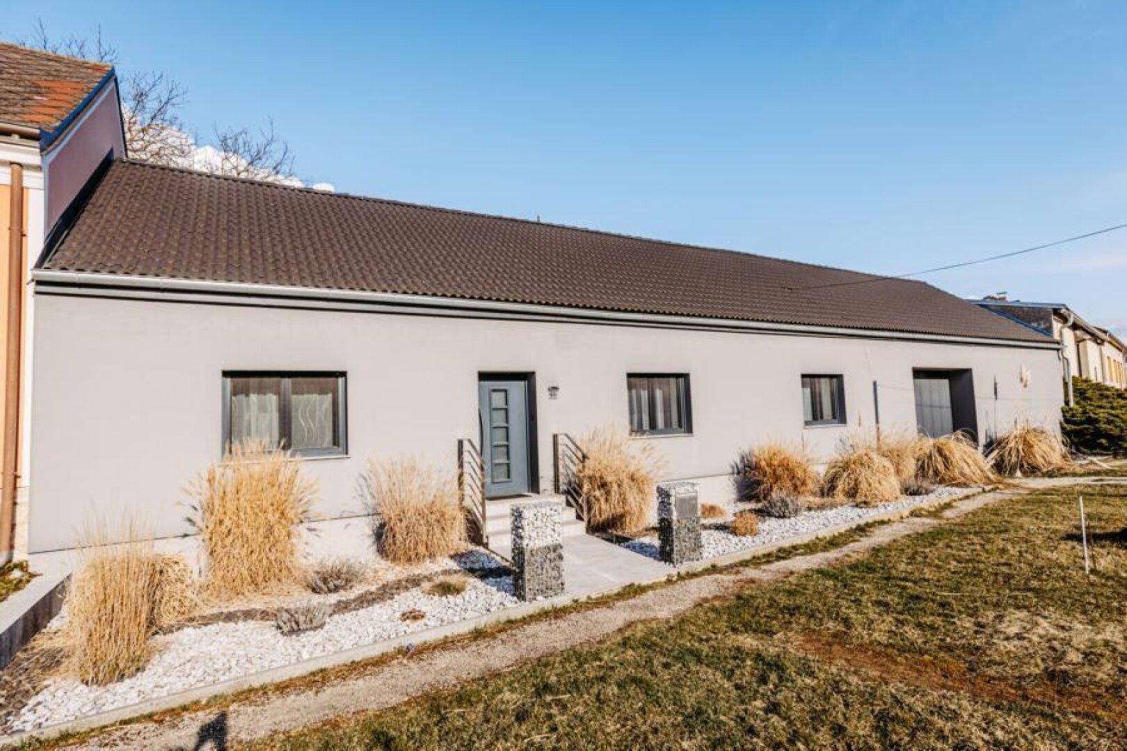 Das Einfamilienhaus präsentiert sich mit heller Fassade, braunem Ziegeldach und einem ordentlichen Vorgarten.