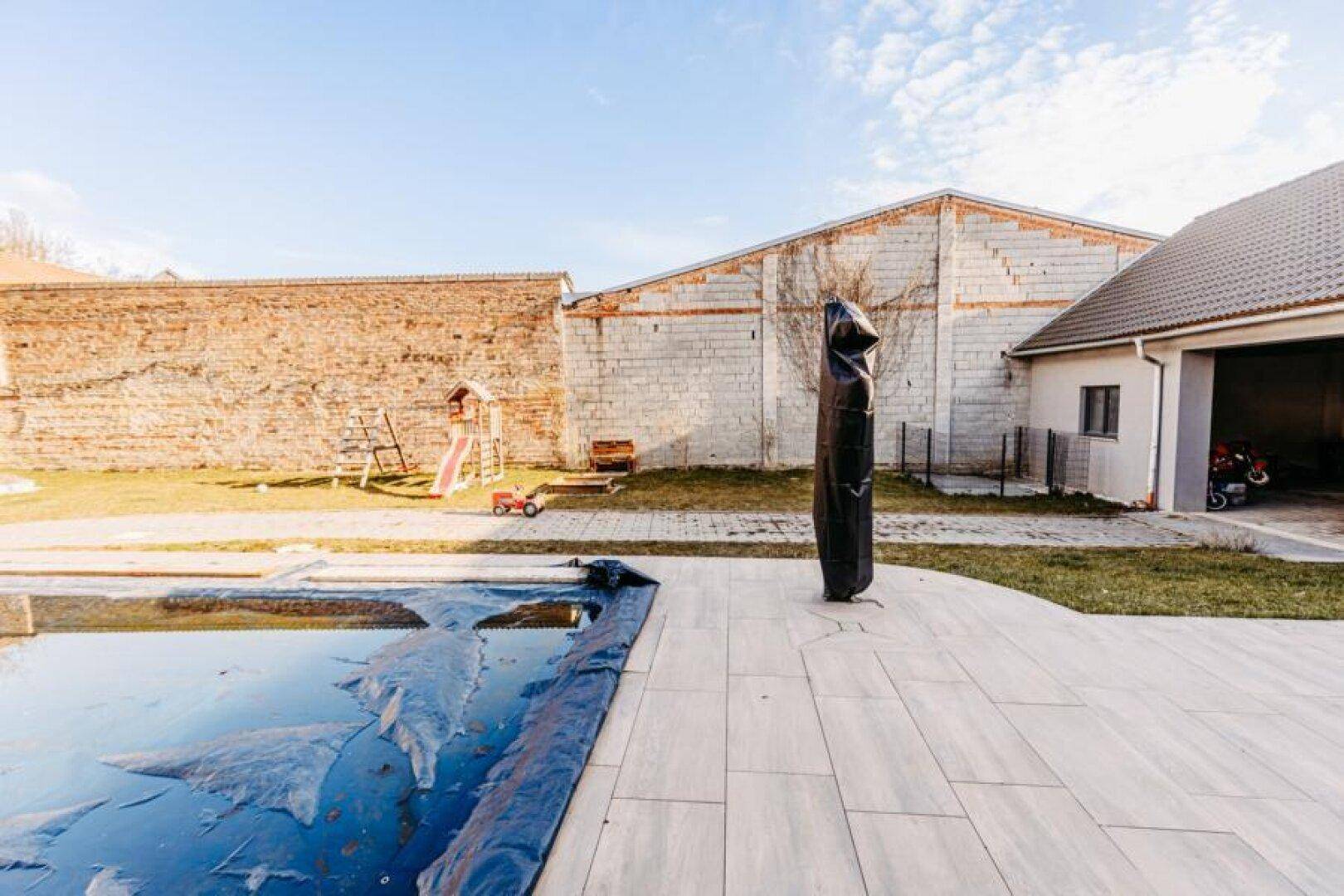 Terrassenbereich mit abgedecktem Pool und einem Spielplatz im hinteren Teil des Gartens.