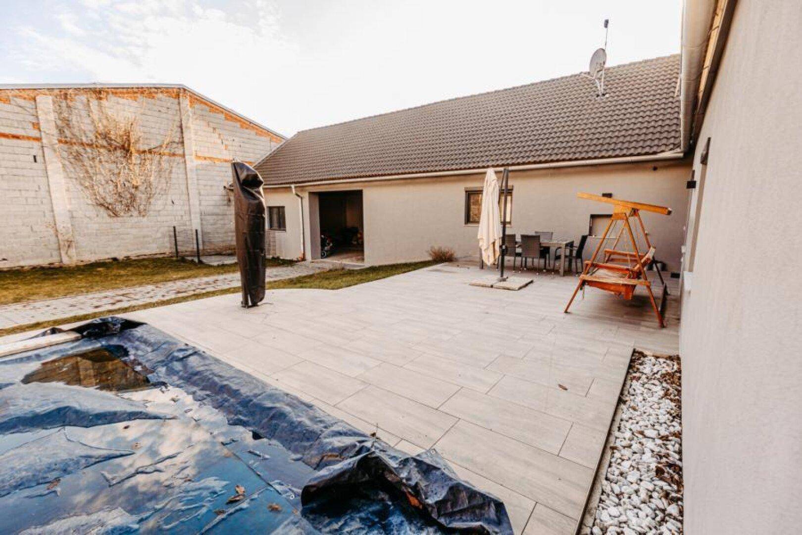 Weitläufige Terrasse mit Pool, Sonnenschirm und Gartenmöbeln, angrenzend an das Haus.